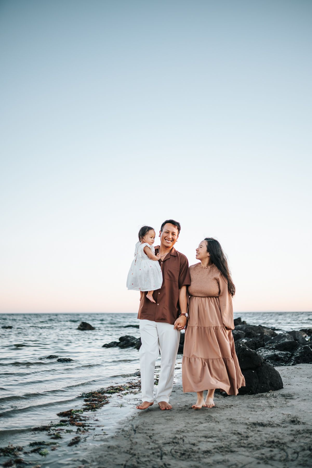 A portrait of a family of 3 walking by the beach during sunset in Williamstown taken by Melbourne Family Photographer.