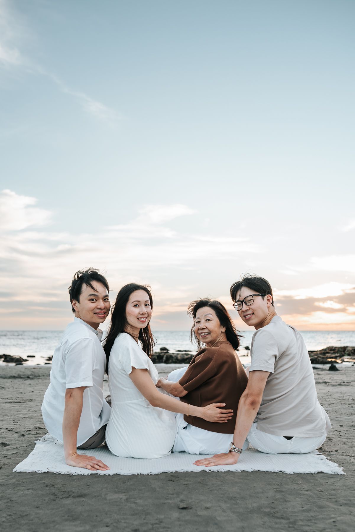 A family portrait of 4 sitting by the beach during sunset taken by a Melbourne Family Photographer.