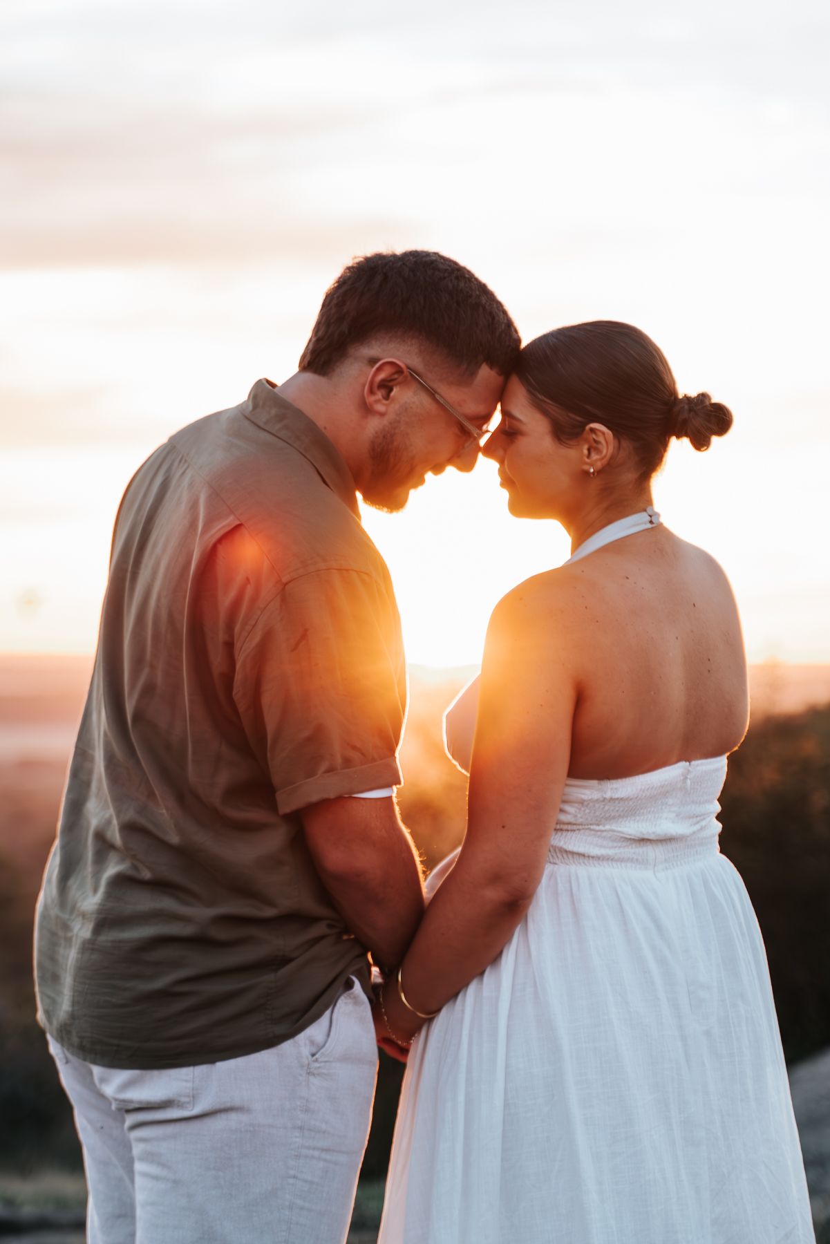 Couple holding hands and touching foreheads at golden sunset, taken during a surprise proposal in Melbourne by a engagement photographer.