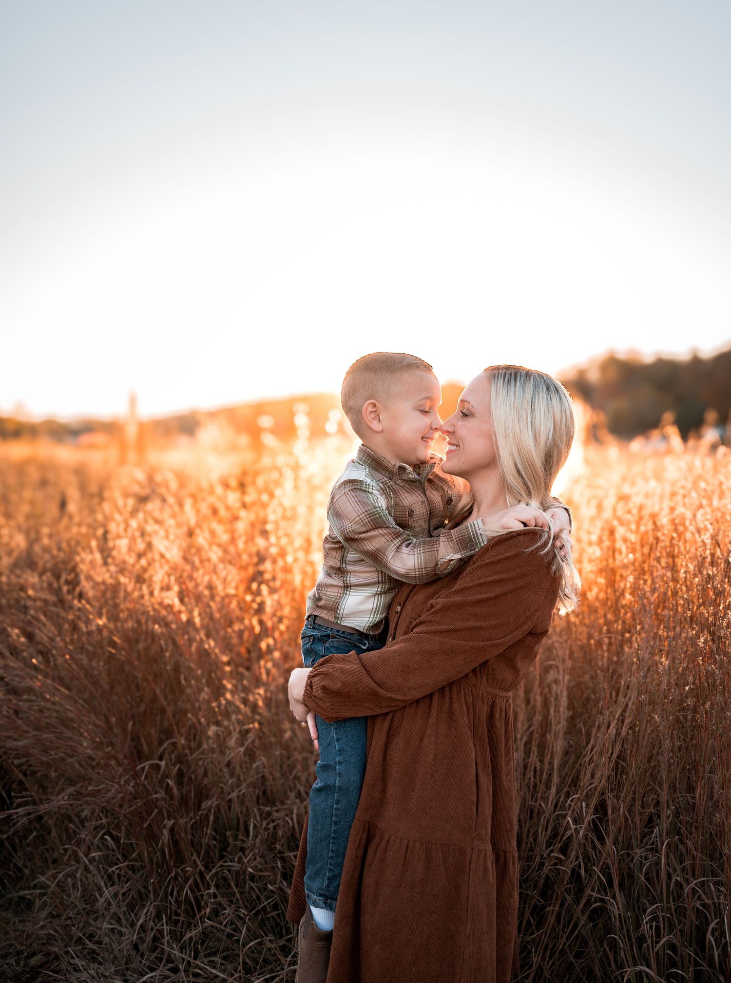A loving embrace between parent and child in a golden wheat field at sunset creates a heartwarming silhouette.