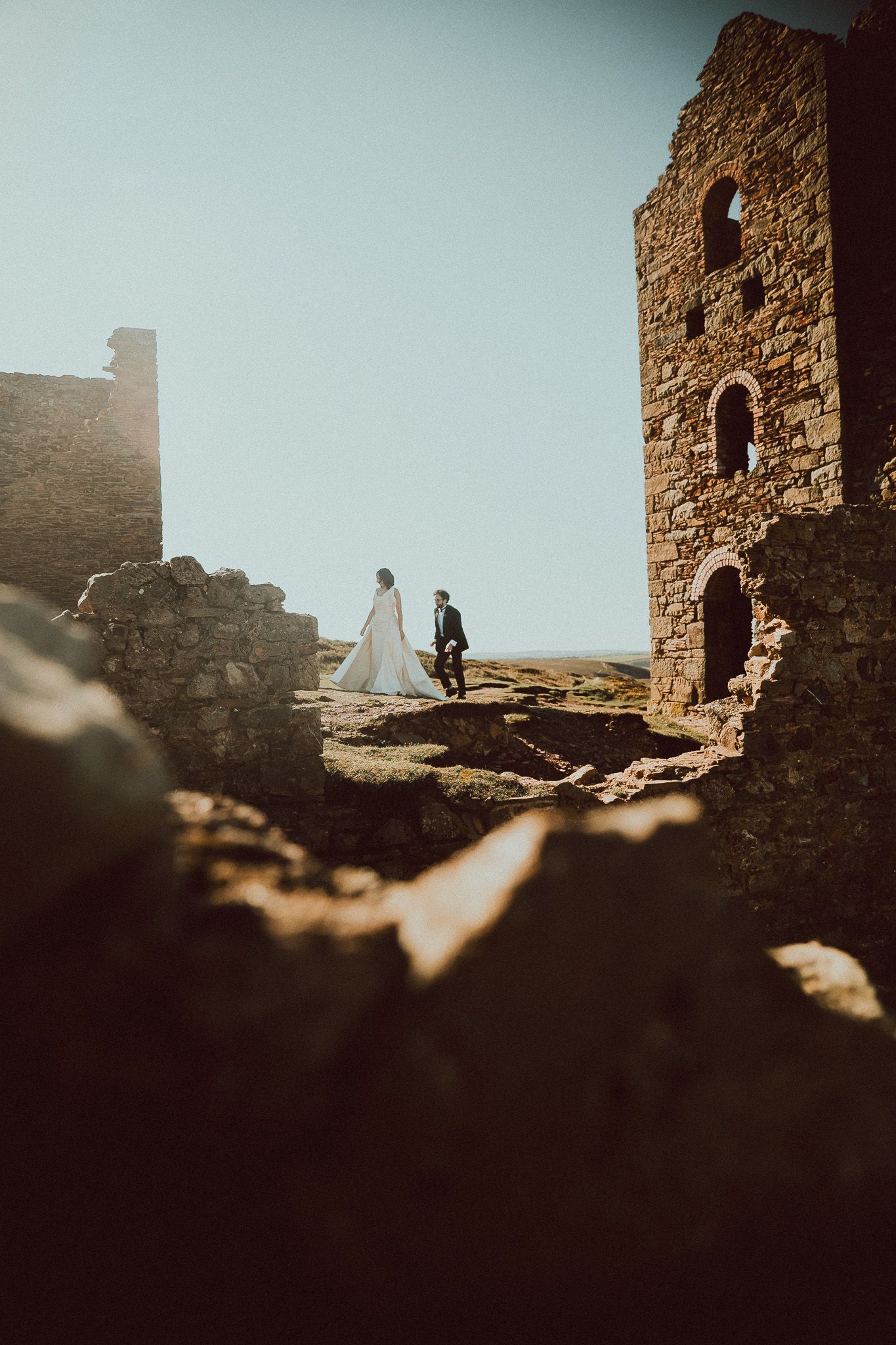 Ancient stone ruins silhouetted against a misty sky with figures exploring the weathered walls and archways.