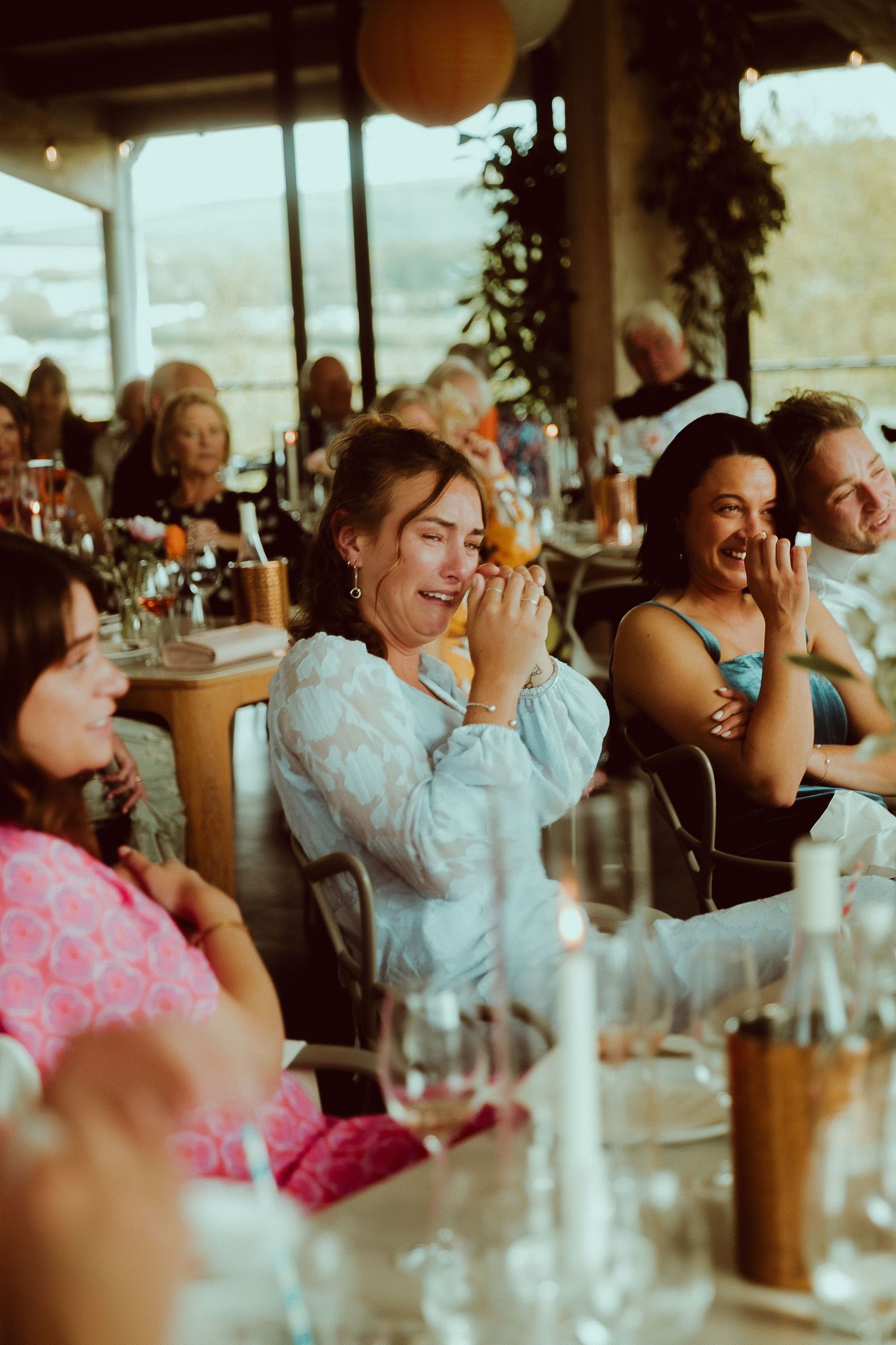 Guests laughing and enjoying themselves at an elegant indoor dining event with candles and wine glasses.