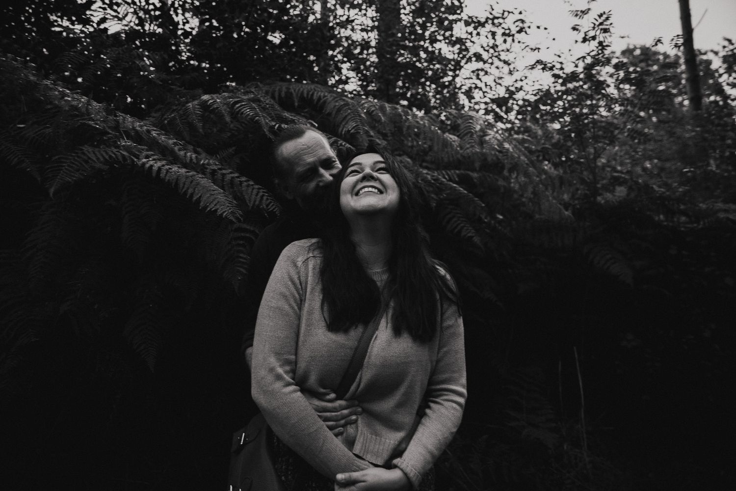 A series of black and white photos showing tender moments between two people embracing in a natural outdoor setting.
