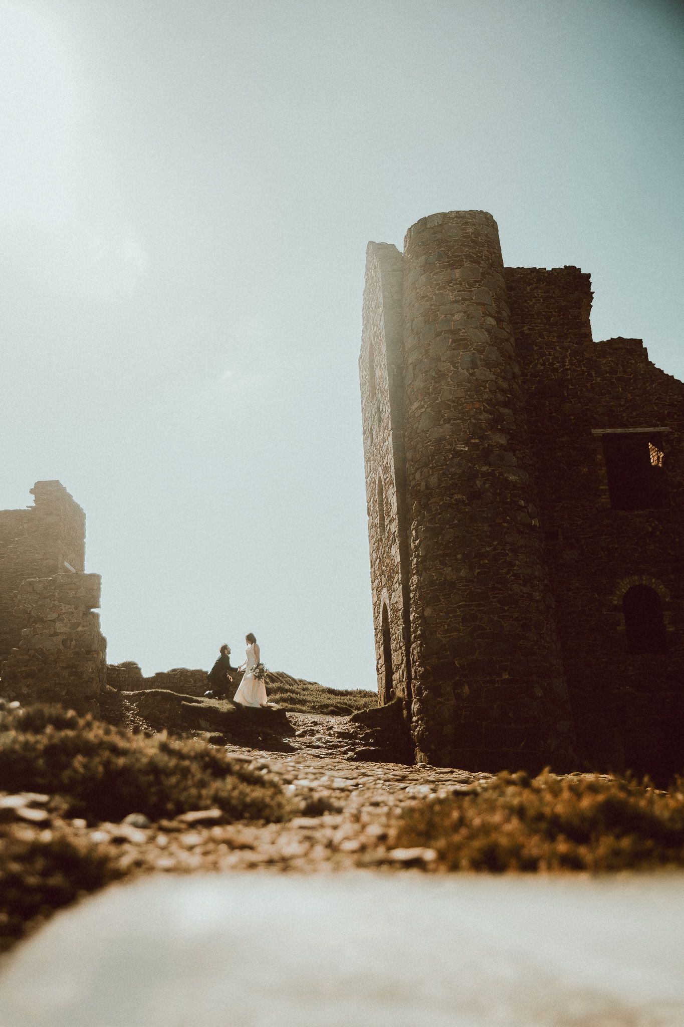 Silhouetted castle ruins stand against a misty sky in a vintage-style sepia photograph.