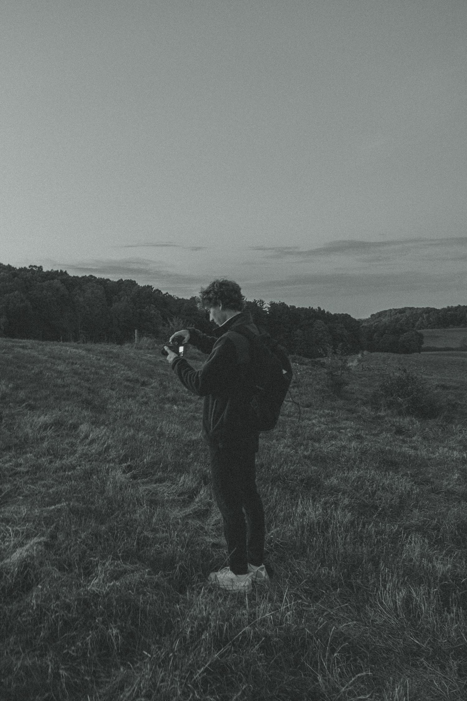 Silhouette of photographer taking pictures in misty field at dusk.