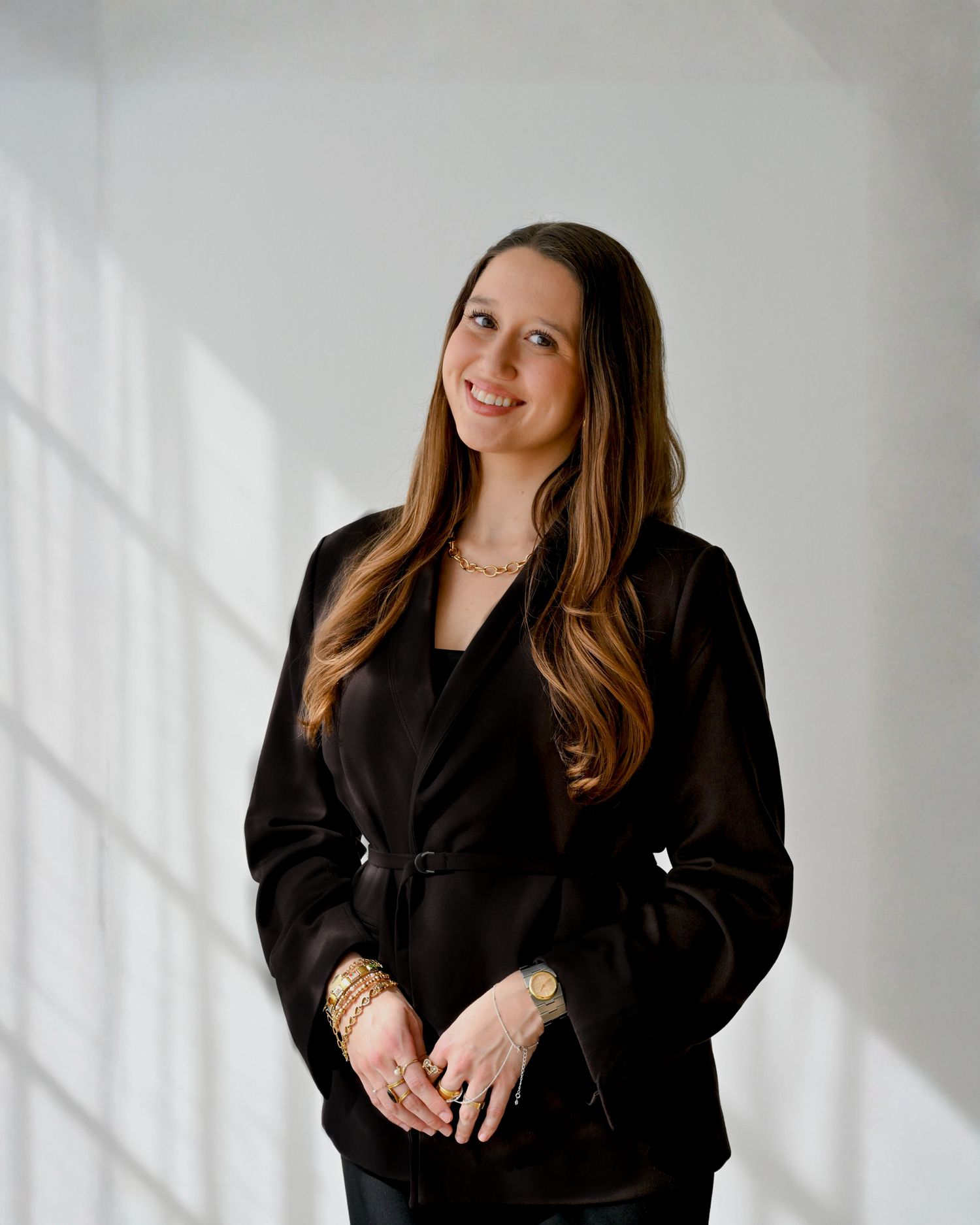A series of artistic portrait photographs showing someone in a black blazer against a white background with natural lighting.