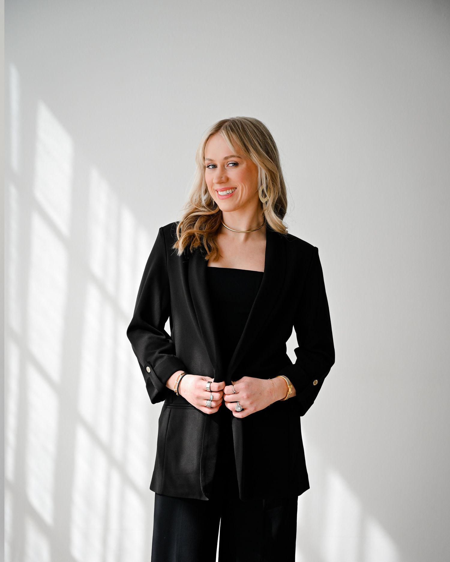 Professional studio portraits featuring a person in a black blazer against a white backdrop with natural lighting.