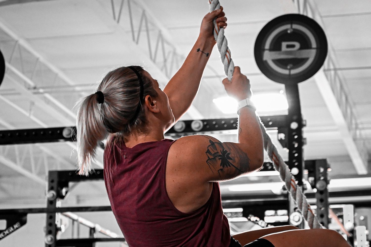 Athlete performing pull-up exercise at gym with dramatic lighting.
