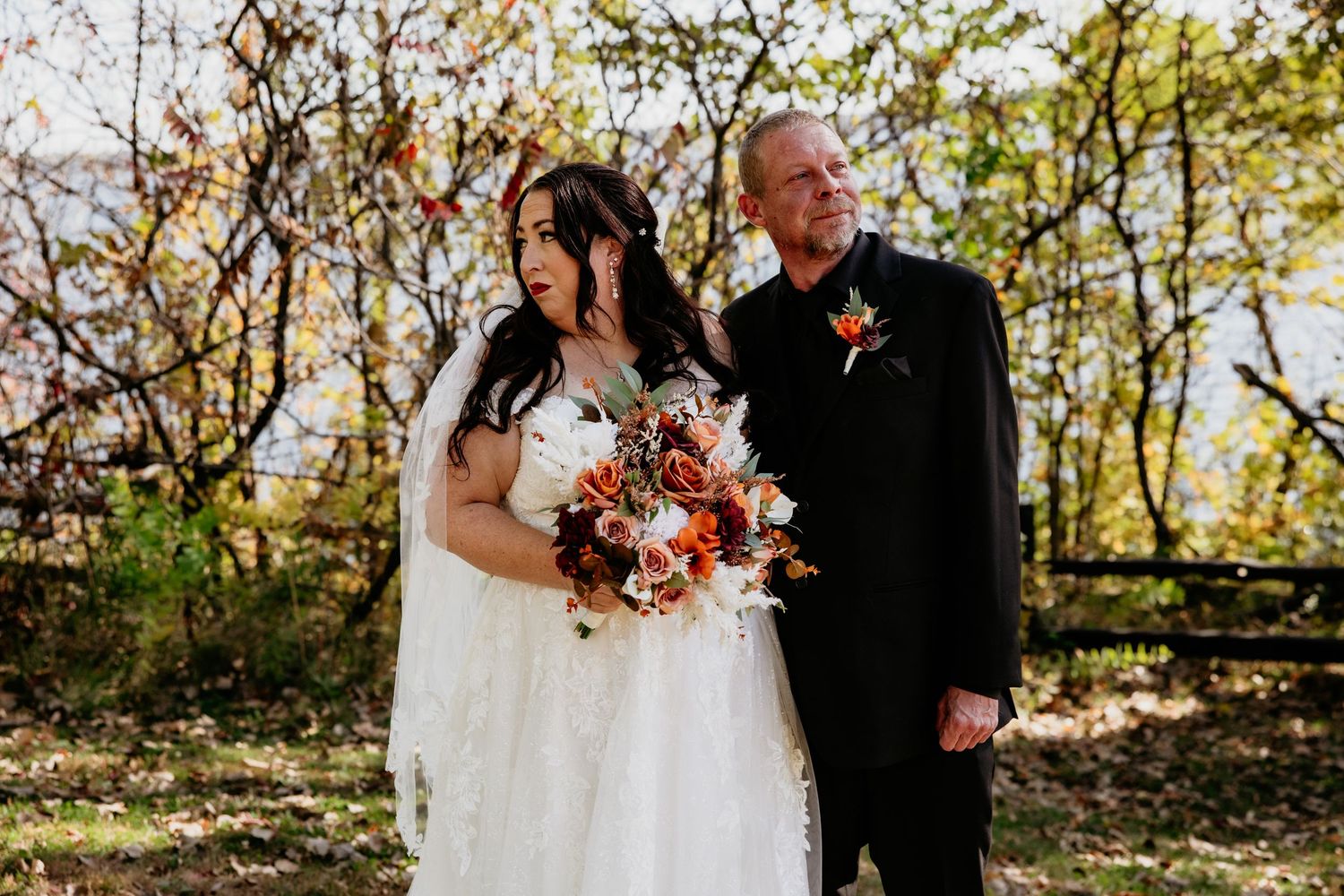Wedding couple posing among autumn trees during golden hour photography session.