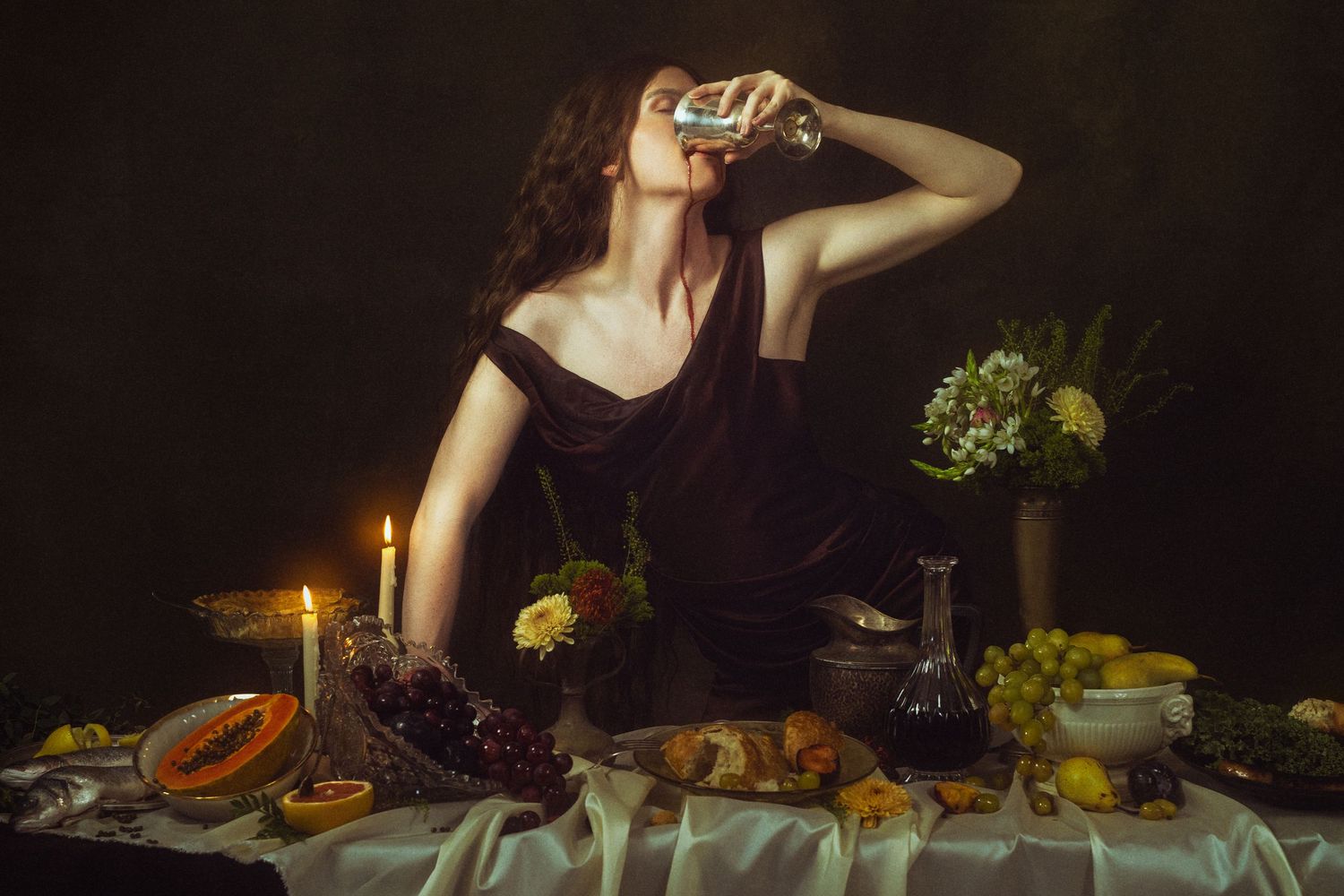 Woman in black dress drinking from glass at candlelit table with fruit and flowers in Dutch master style.