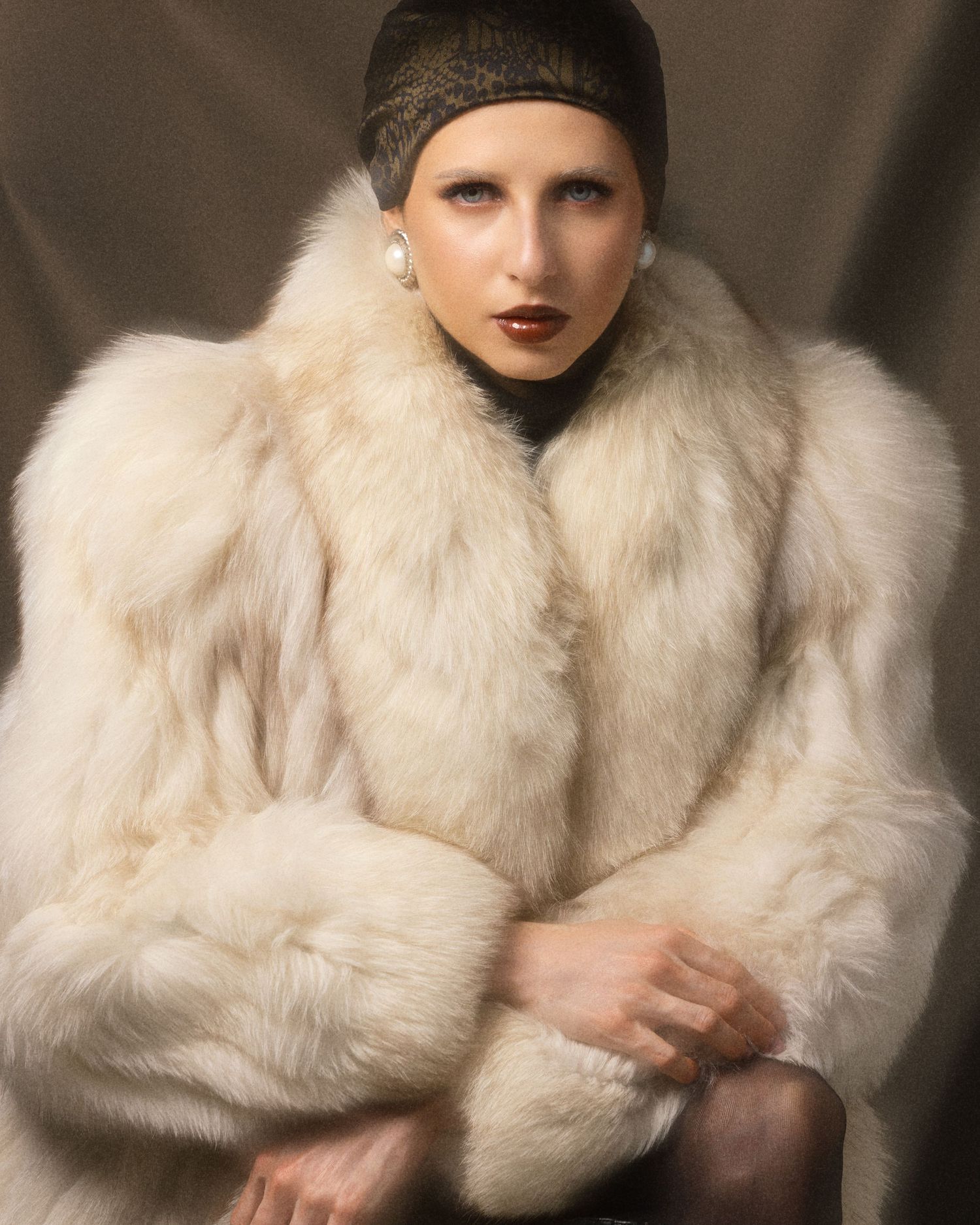 Woman wearing white fur coat and beaded headpiece in vintage glamour portrait photography.