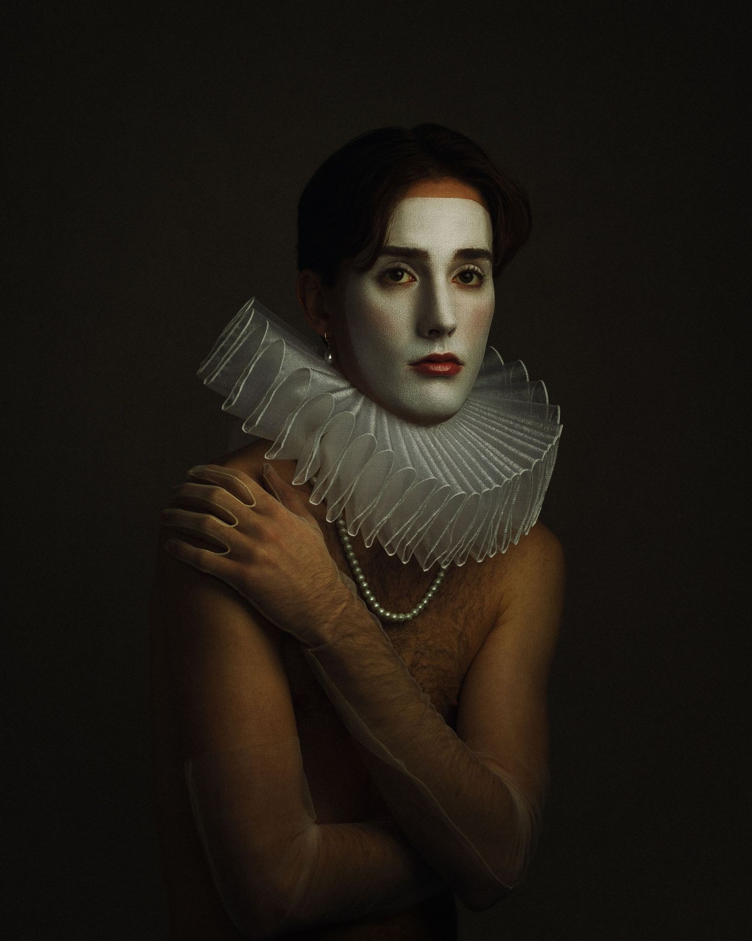Person with white face paint and Elizabethan ruff collar poses in dramatic Renaissance-style portrait.