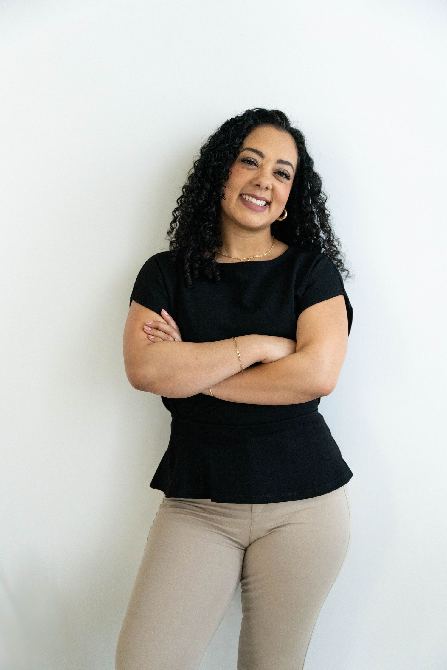 A series of casual lifestyle photos showing a person in a black top and beige pants posing against a white wall.