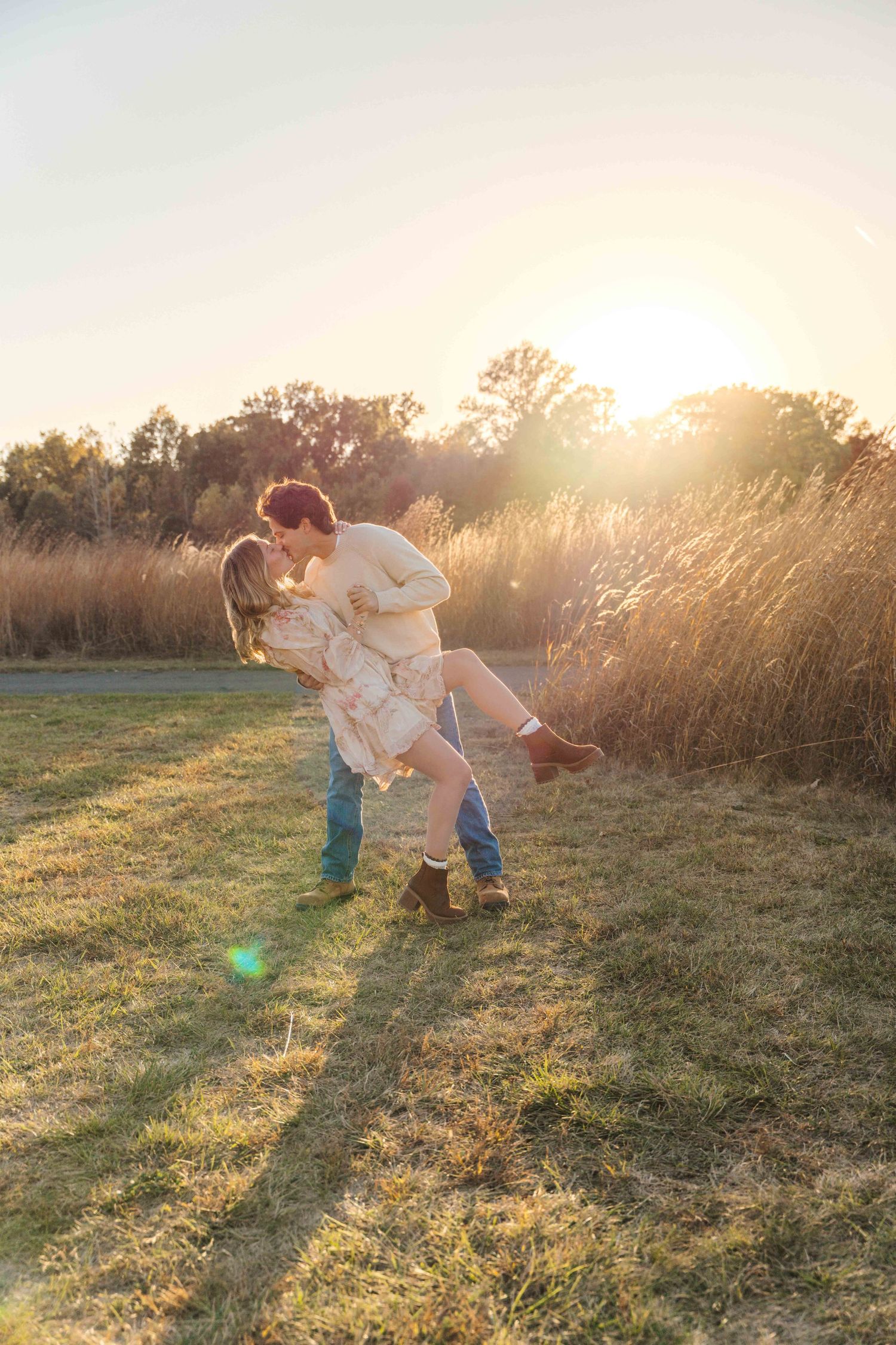 A family plays together in a sun-drenched meadow at golden hour, creating long shadows across the grass.