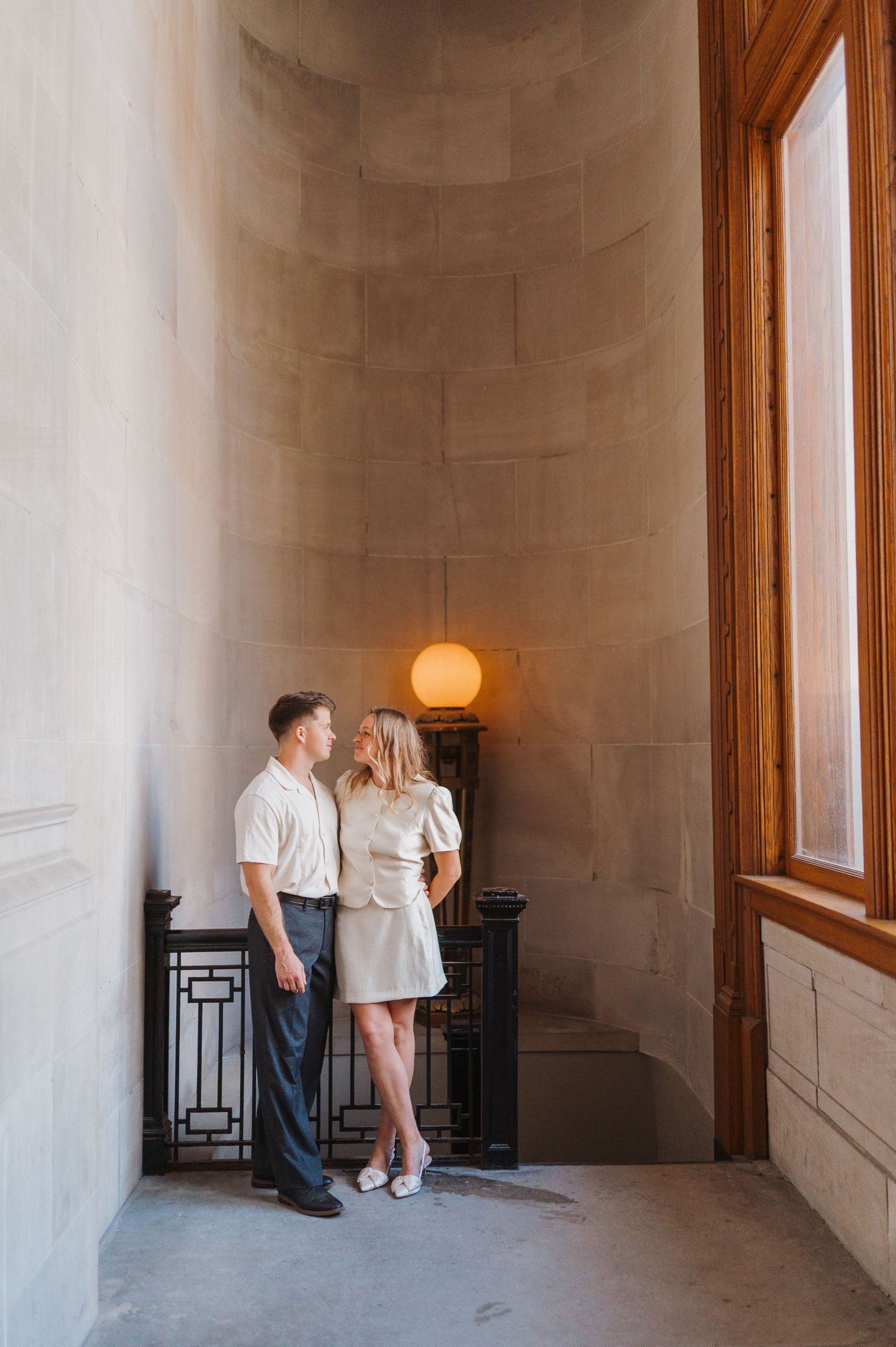 Couple sharing a romantic moment in an elegant stone alcove with warm globe lamp lighting.