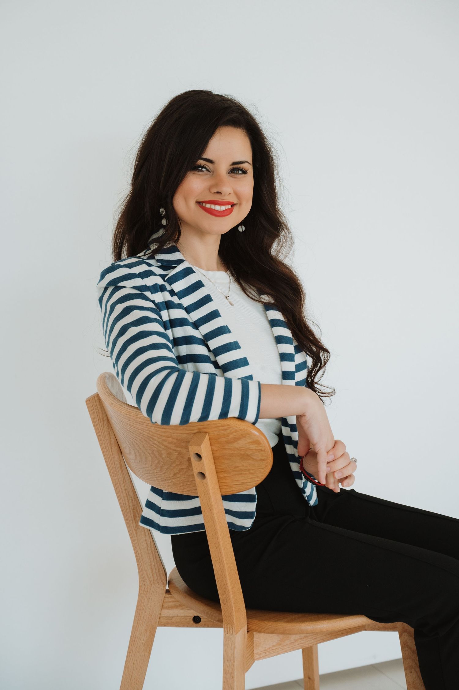 PHTA CPO course manager in striped blazer sitting on wooden chair against white background.