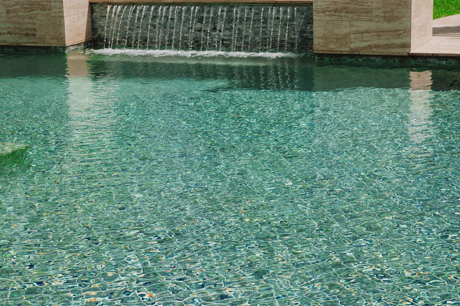 A serene turquoise swimming pool with a decorative waterfall feature and mosaic tile flooring.