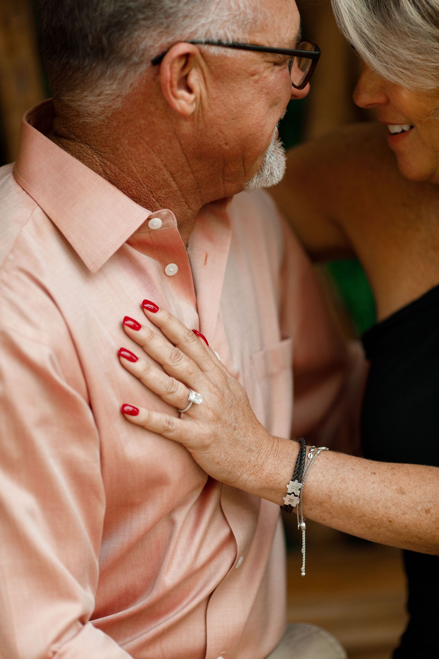 Close up of hands with red nails touching pink shirt in intimate romantic moment.