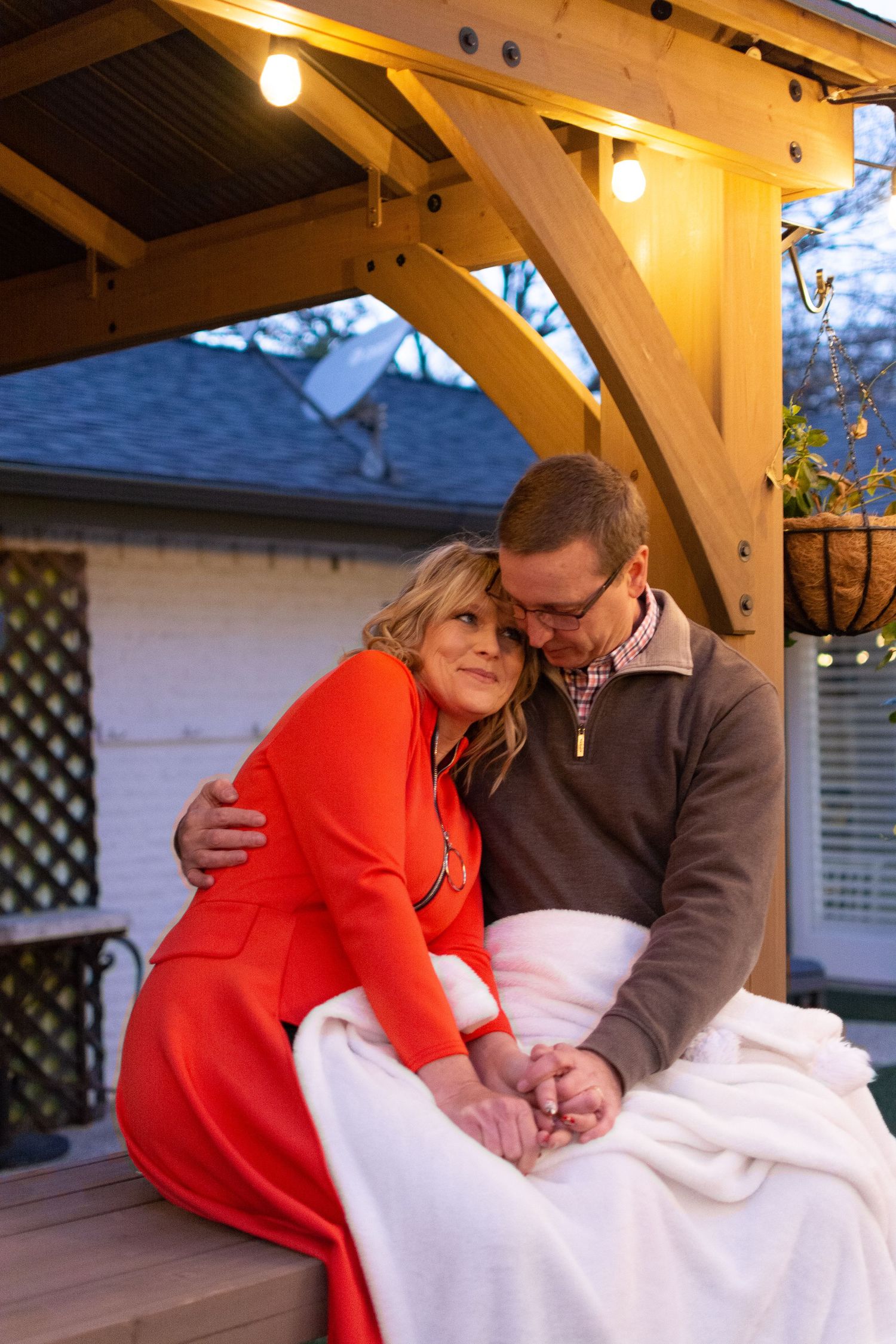 Happy couple cuddle up under a throw blanket outside. Photo Credit: Gernelle Nelson. Plano, TX