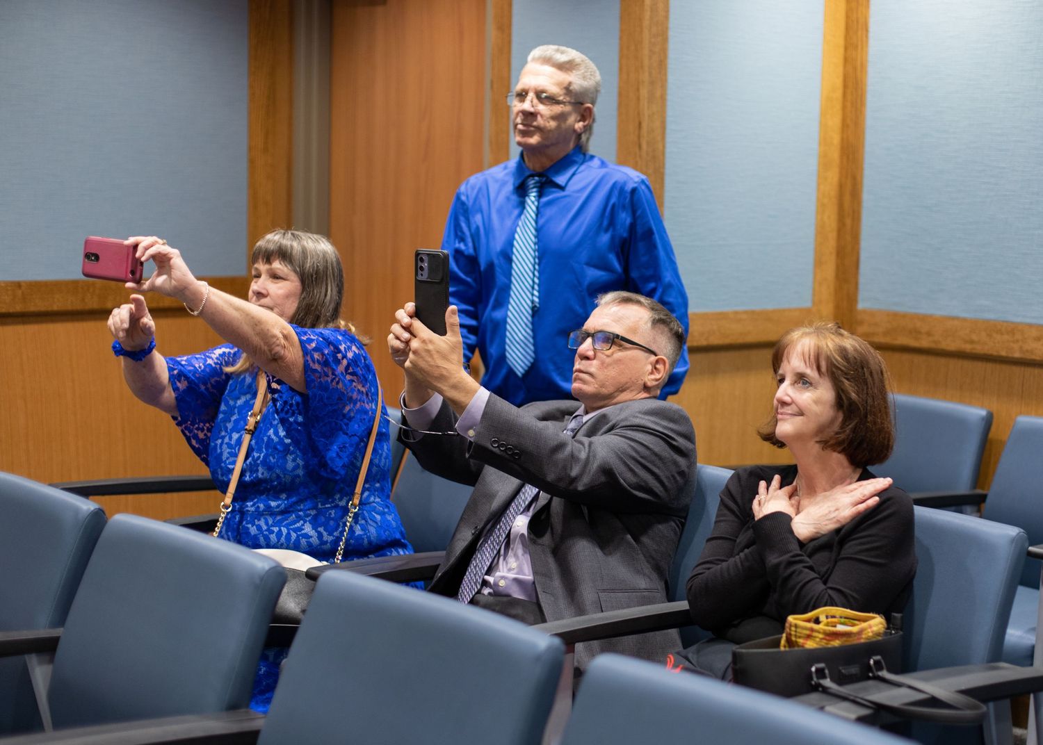 Wedding guests in blue attire capturing photos during the courthouse ceremony.