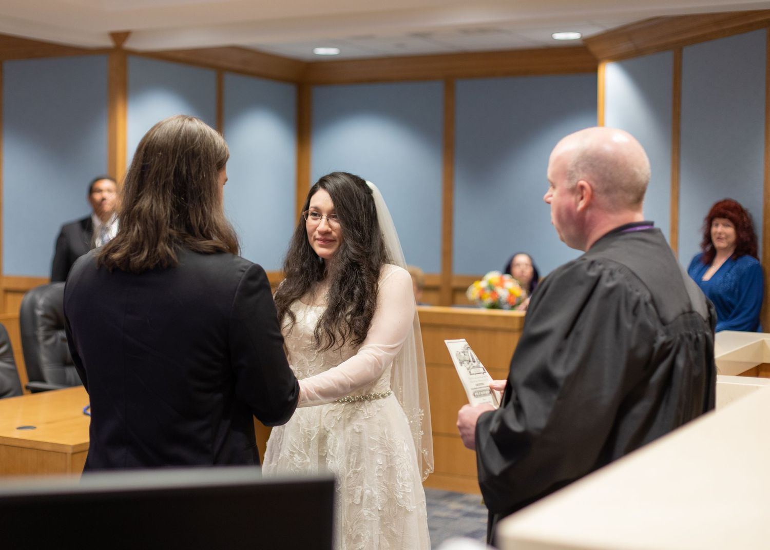 A wedding ceremony taking place in a courthouse with a judge presiding over the couple's vows.
