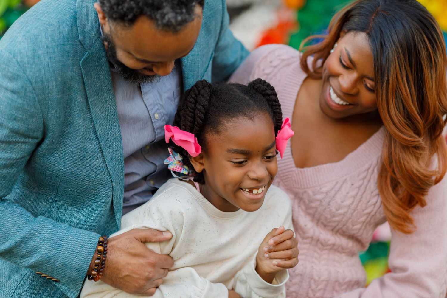 Happy Black family with young girl sharing a joyful moment together outdoors.