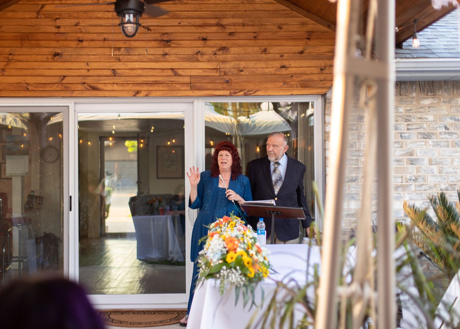 A couple stands at a wedding podium with yellow floral arrangements.