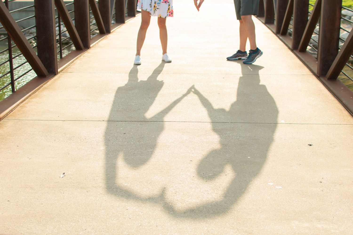 Creative shadow silhouette of couple holding hands cast on concrete bridge.
