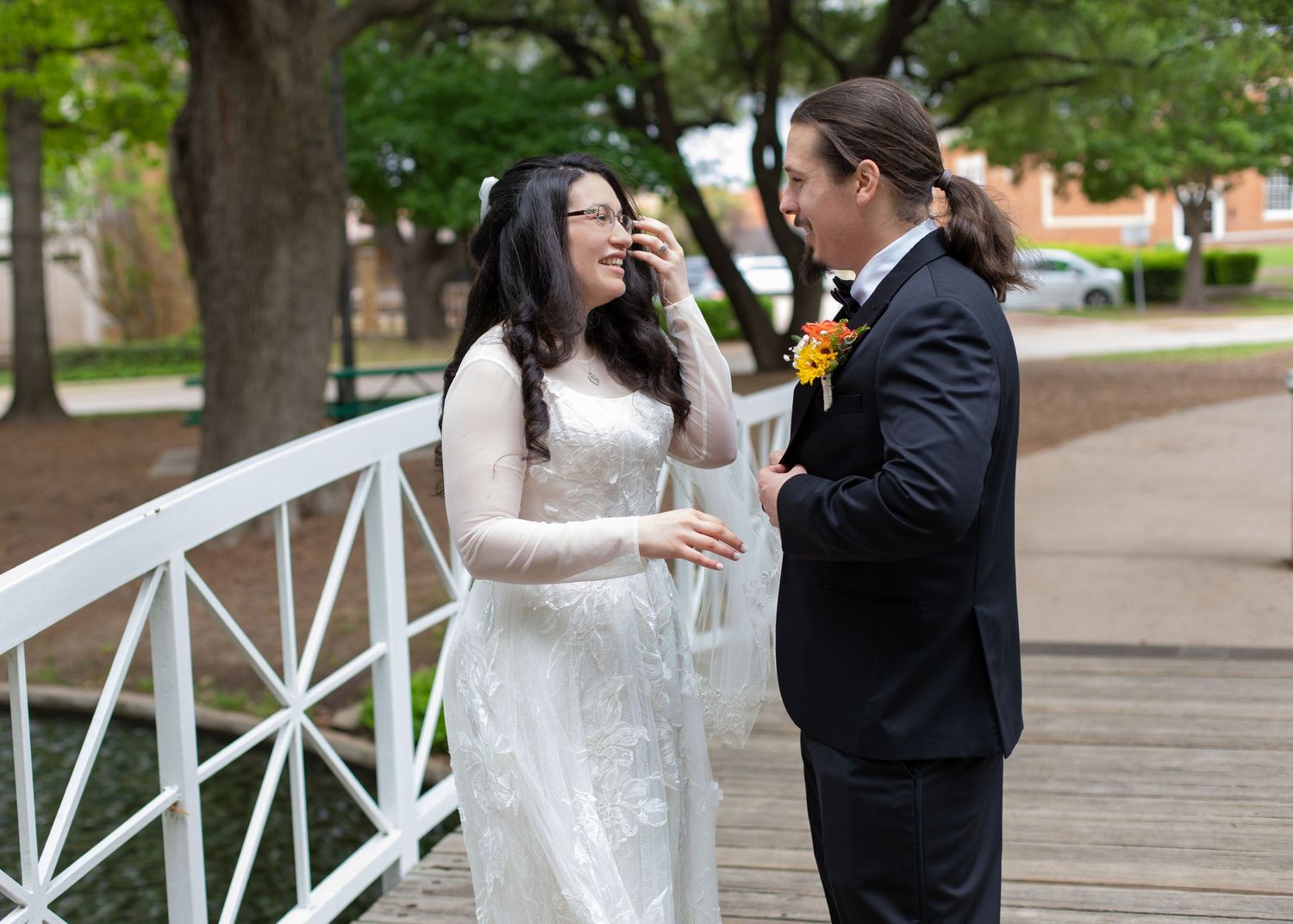 A couple shares a candid laughing moment during their wedding photos on a white bridge.