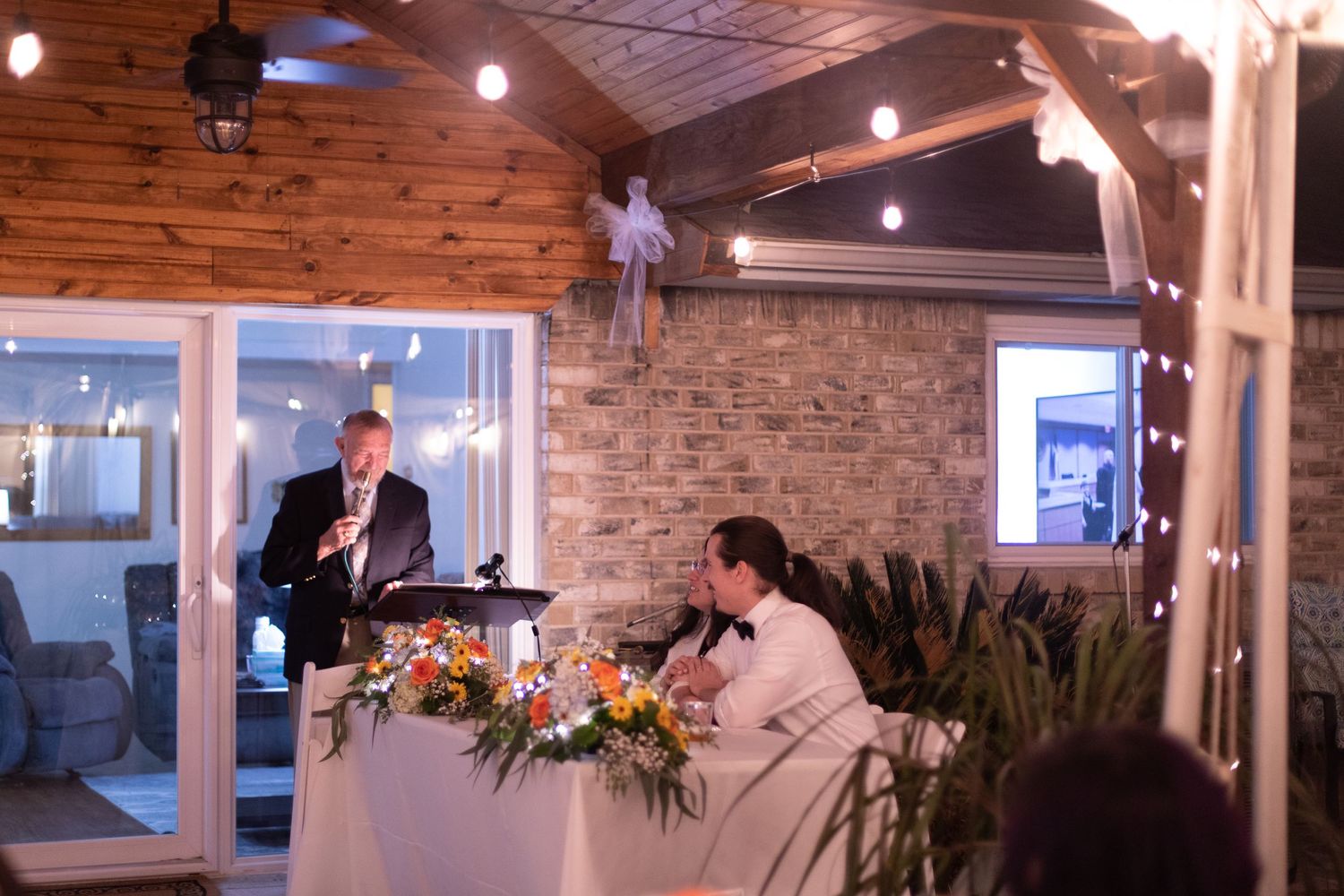 Reception venue with wooden beams and string lights creating ambient atmosphere.
