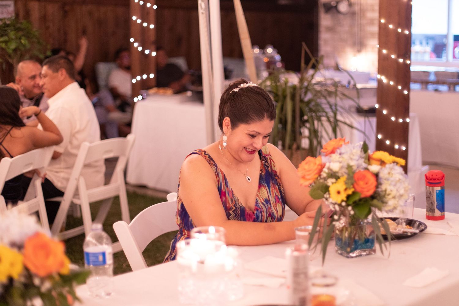 A guest in purple enjoying a meal at a reception with floral centerpieces.