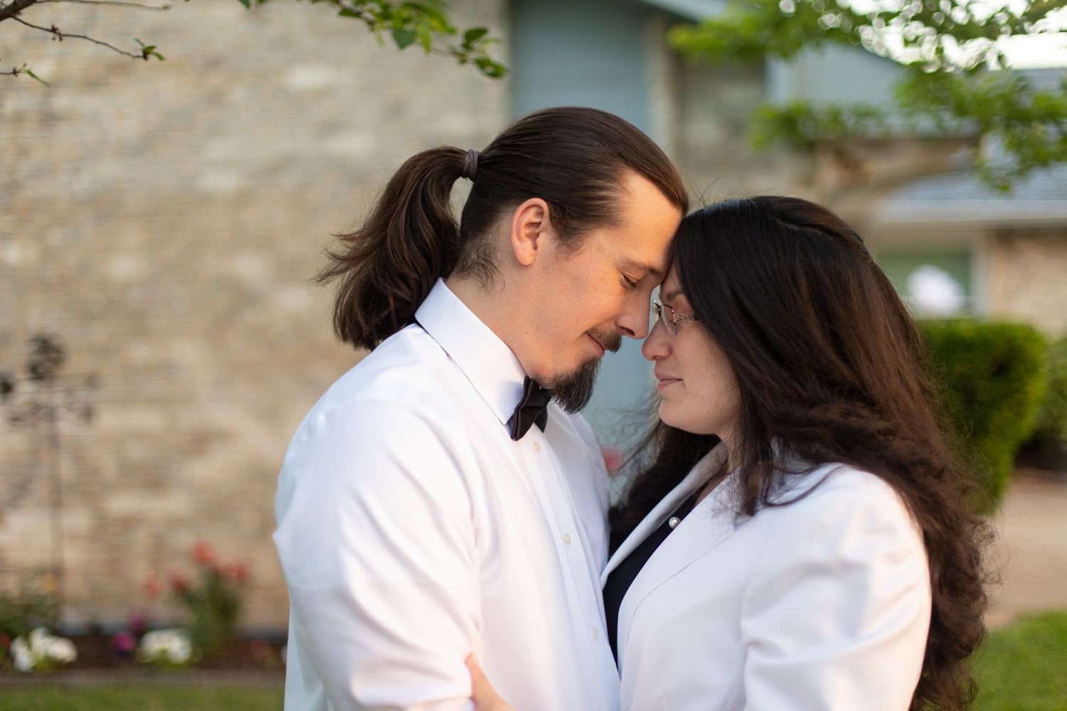 Intimate close-up moment between couple in matching white formal wear.