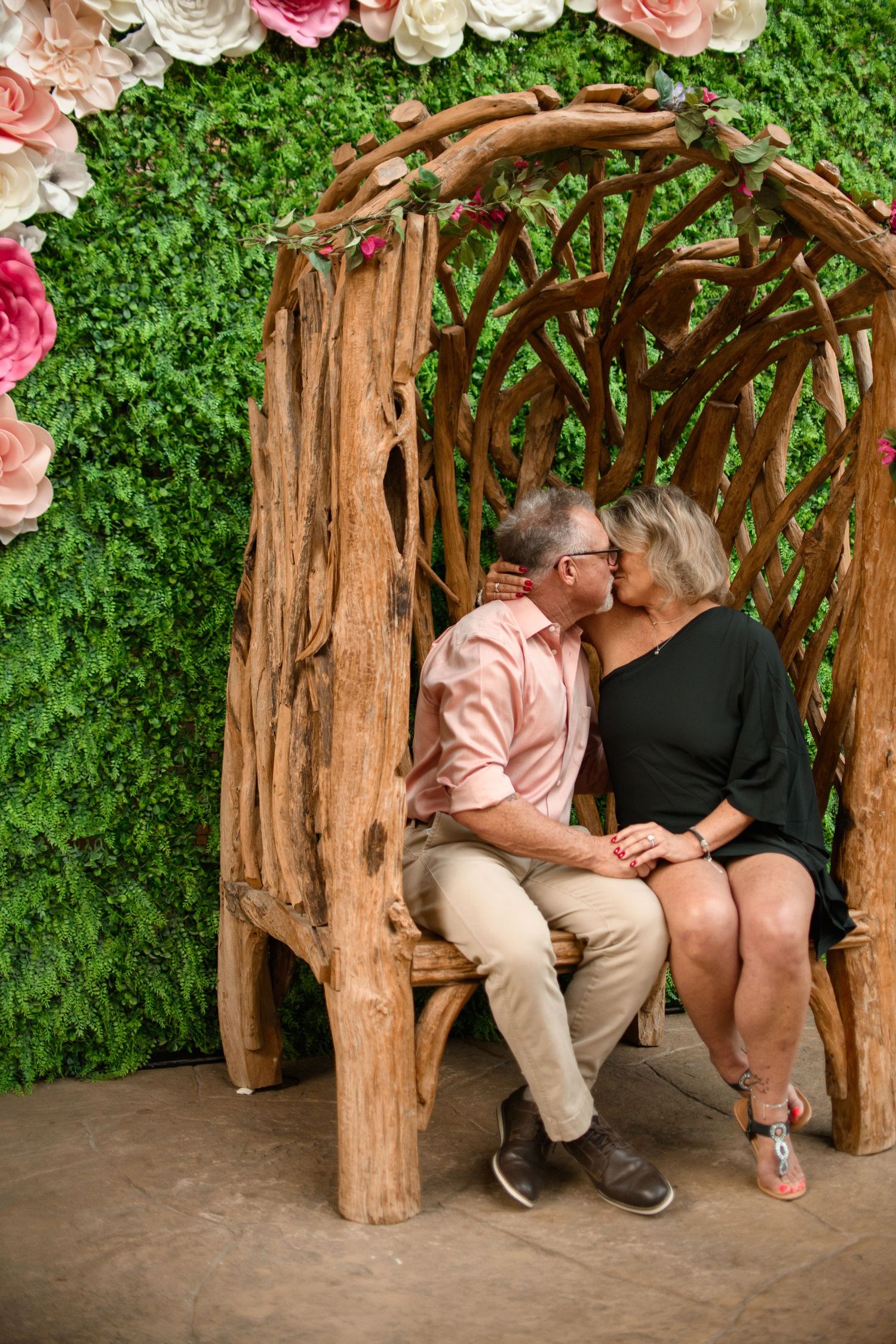 Intimate moment shared on rustic wooden bench surrounded by floral garden wall.