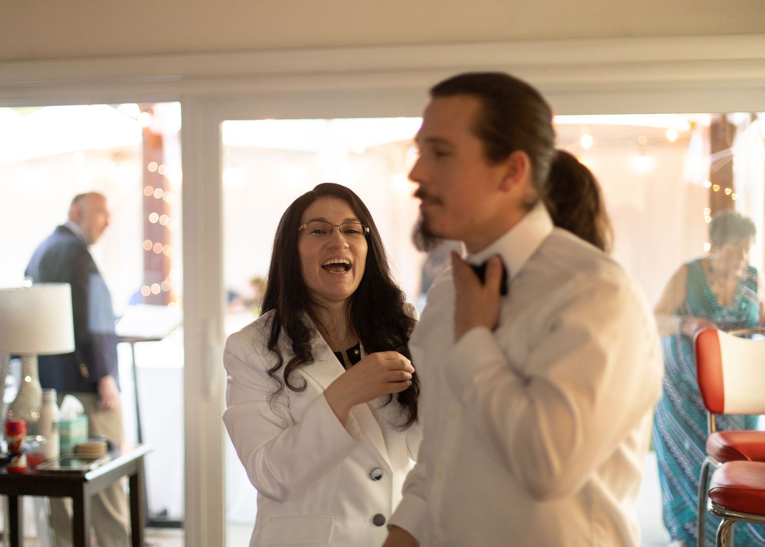 Joyful moment as couple adjusts bowties while laughing indoors.
