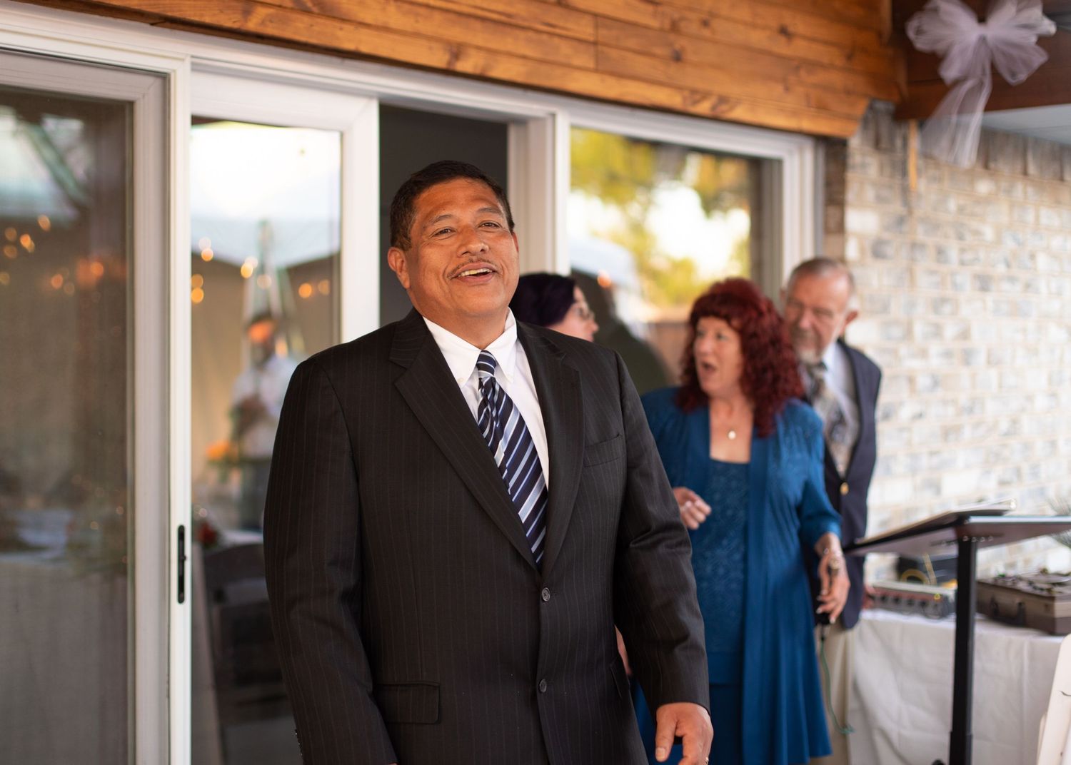A person in formal attire stands outside during a wedding event.