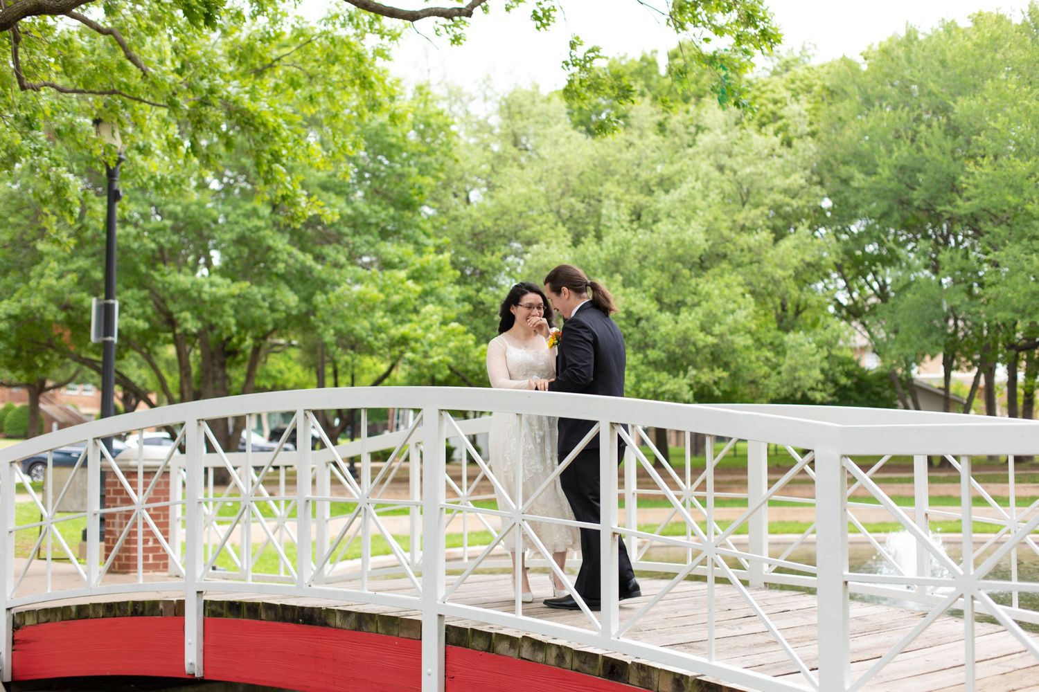 A couple shares a joyful moment during their wedding photoshoot on a decorative bridge.