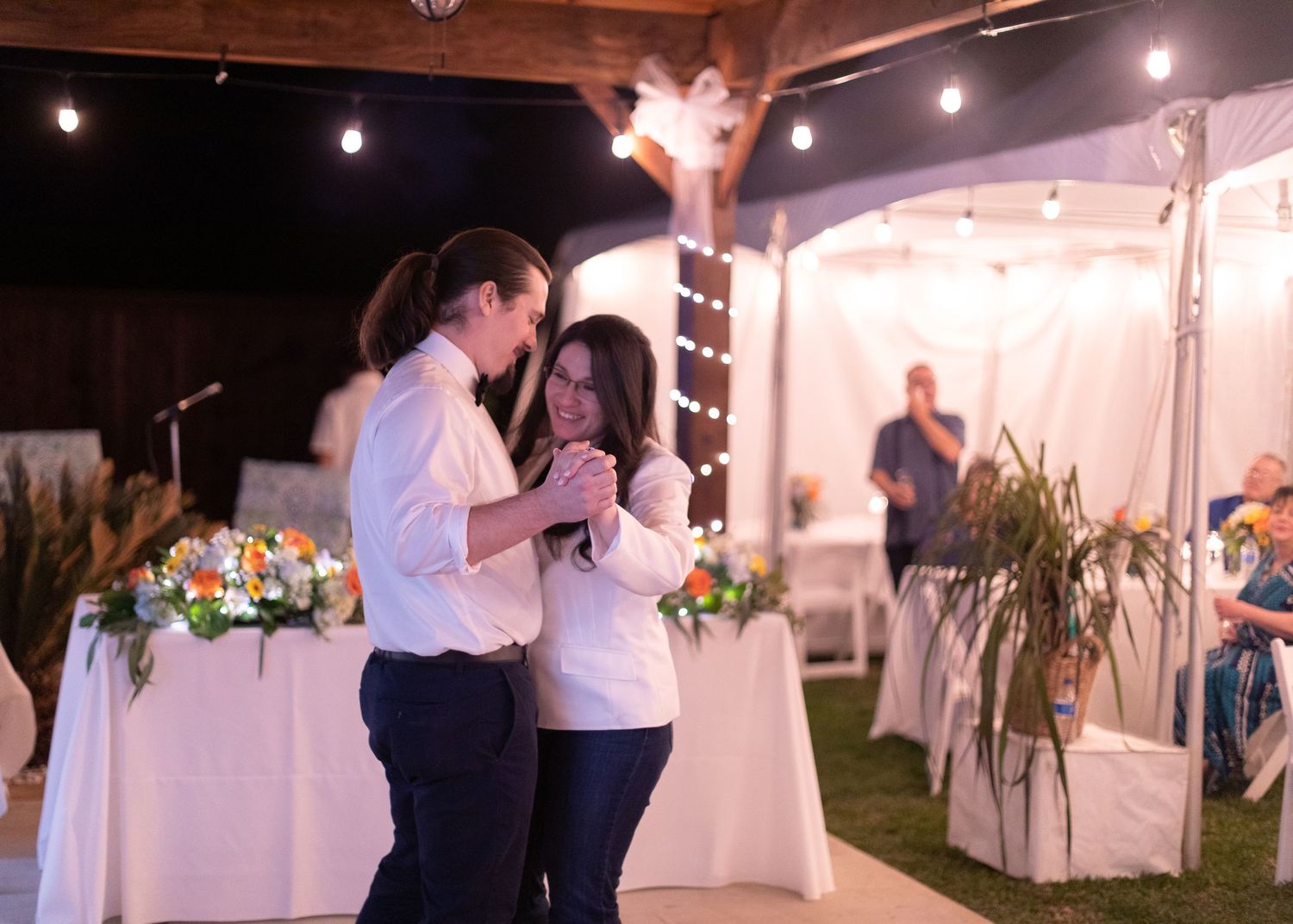A couple sharing a romantic slow dance at an evening wedding reception.
