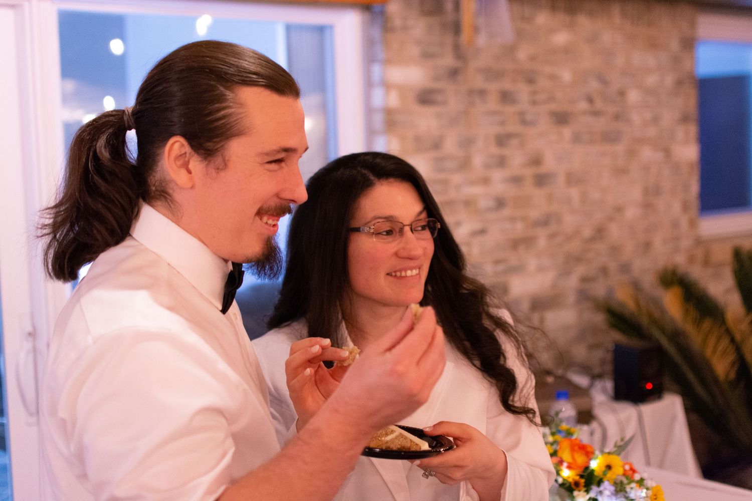 Couple sharing a moment while tasting food at an indoor reception.