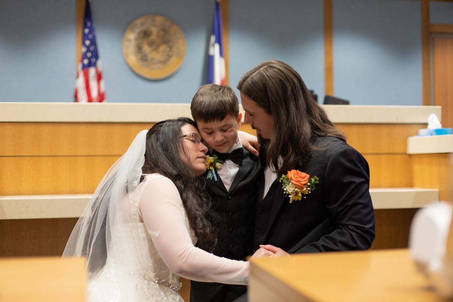 Newlyweds share their first kiss in front of the judge's bench at courthouse wedding.