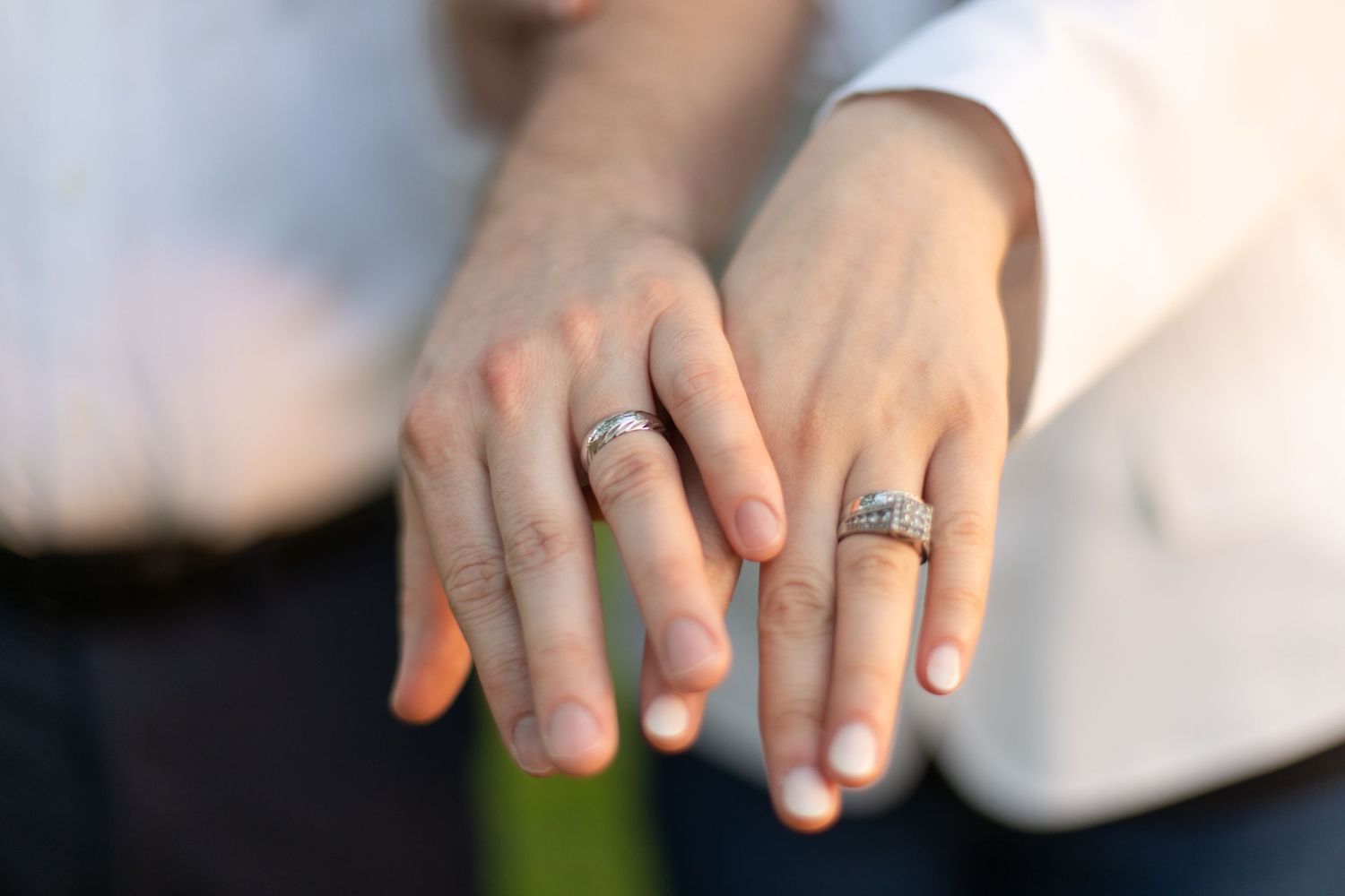 Close up of hands displaying engagement or wedding rings.