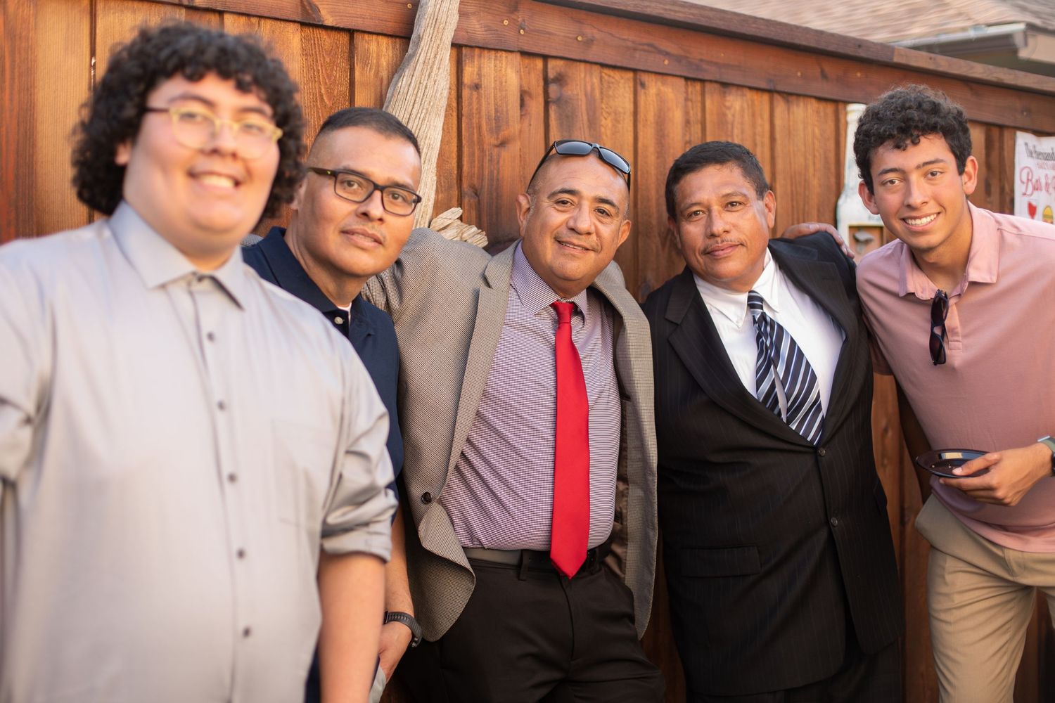 A group of five groomsmen pose together for a formal wedding photo.