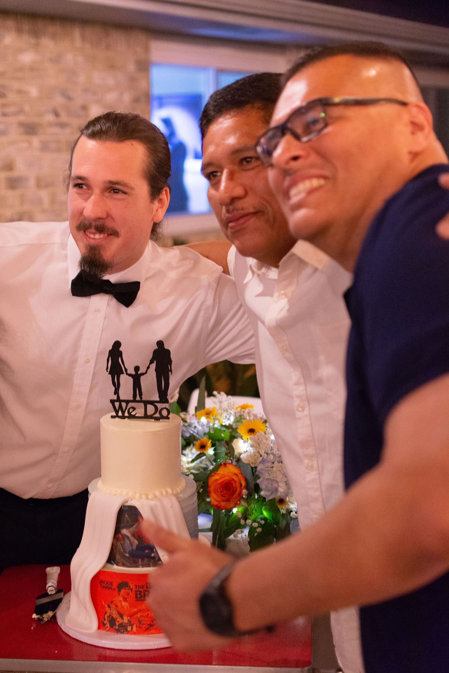 Wedding cake decorated with a silhouette topper and colorful floral arrangements.