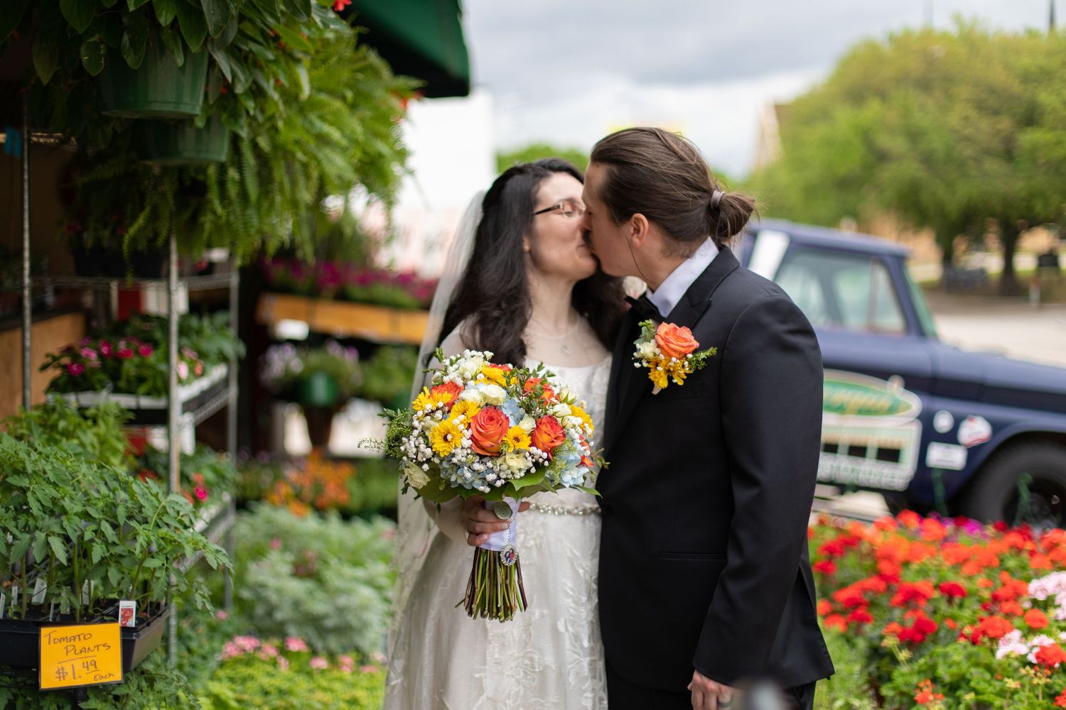 A tender moment shared between a couple surrounded by bright flowers at a garden nursery.