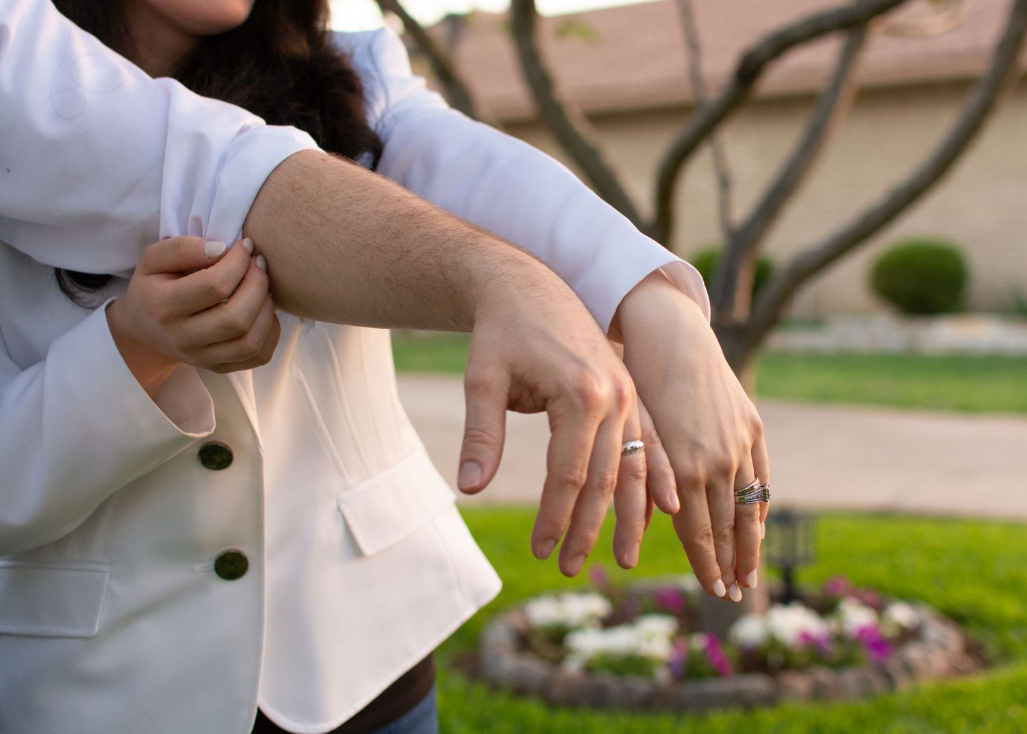 Hands showing off jewelry against a garden background with flowers.