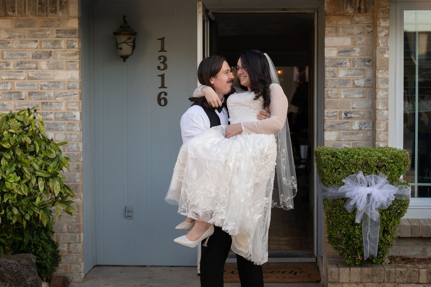 A couple shares a romantic moment at their doorstep during a wedding celebration.