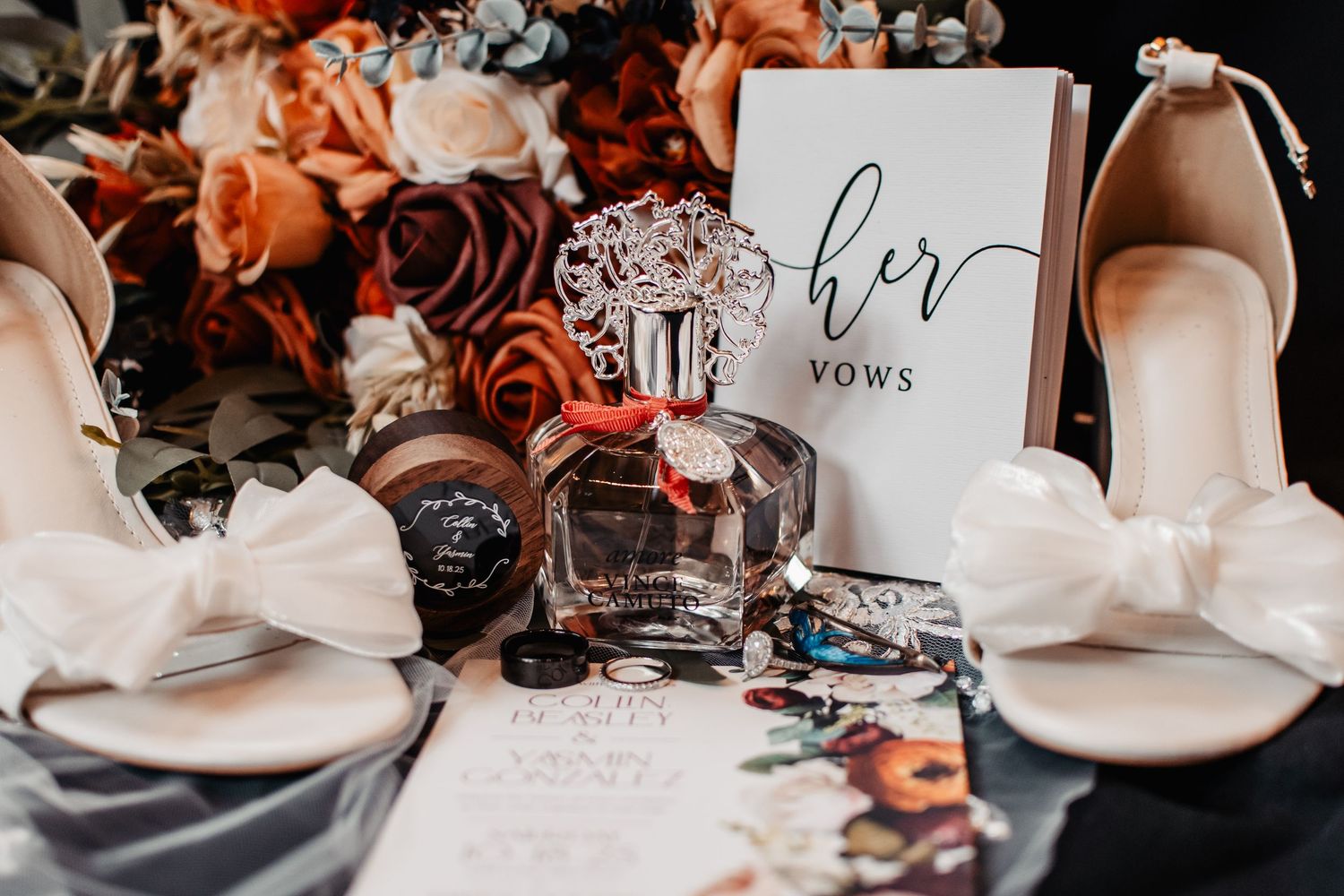 Wedding flat lay with white heels, vow book, perfume bottle, watch, and burnt orange floral bouquet.