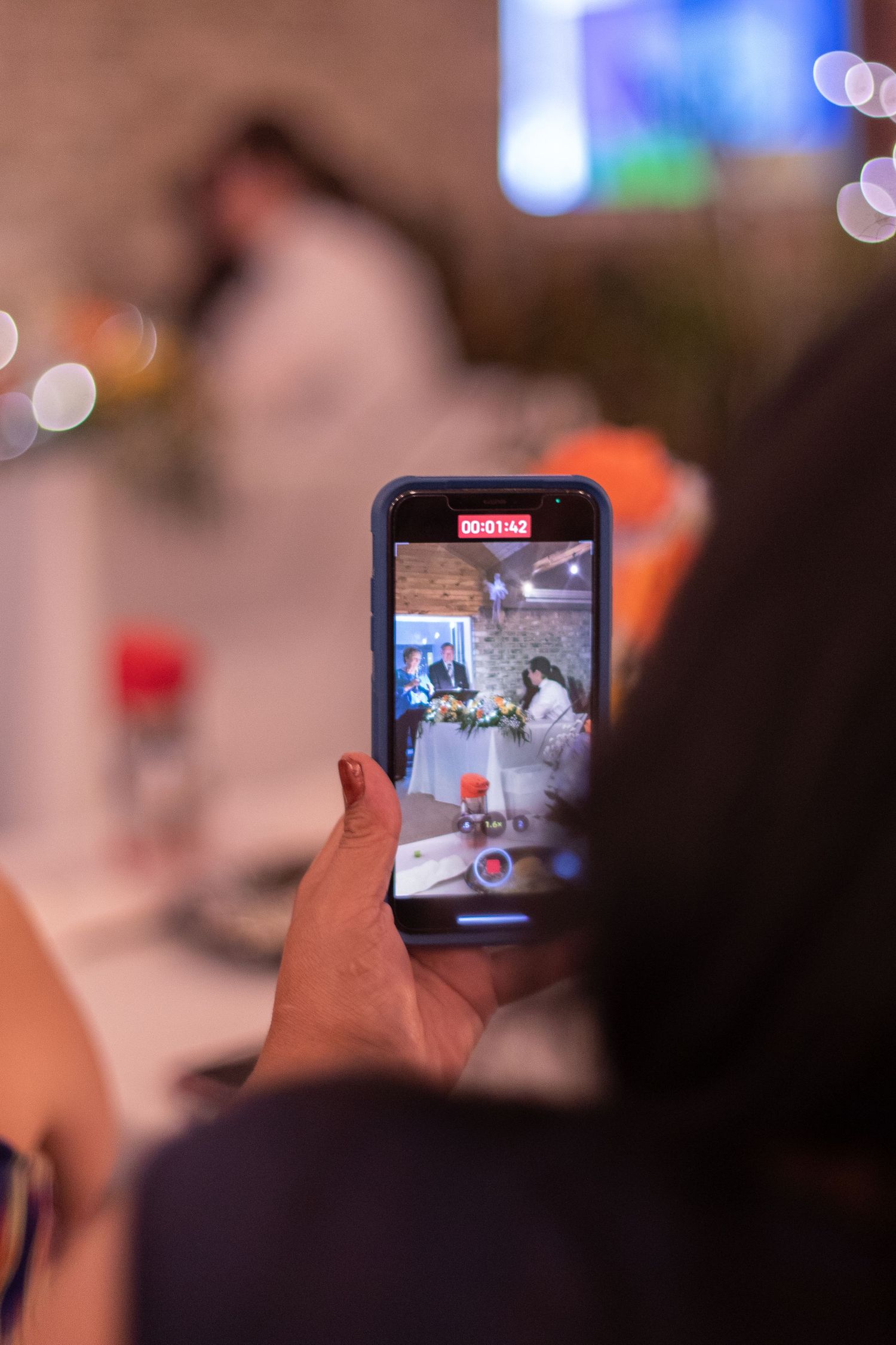 Someone holds up a smartphone displaying a live video feed at an indoor event.