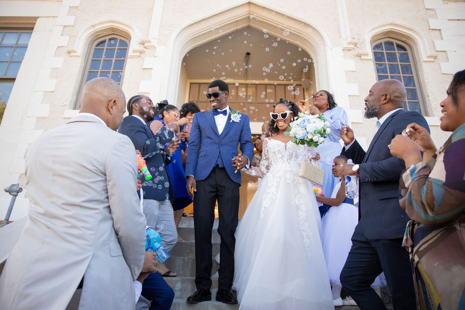 Joyful newlyweds exit church ceremony as guests celebrate with confetti on the front steps.