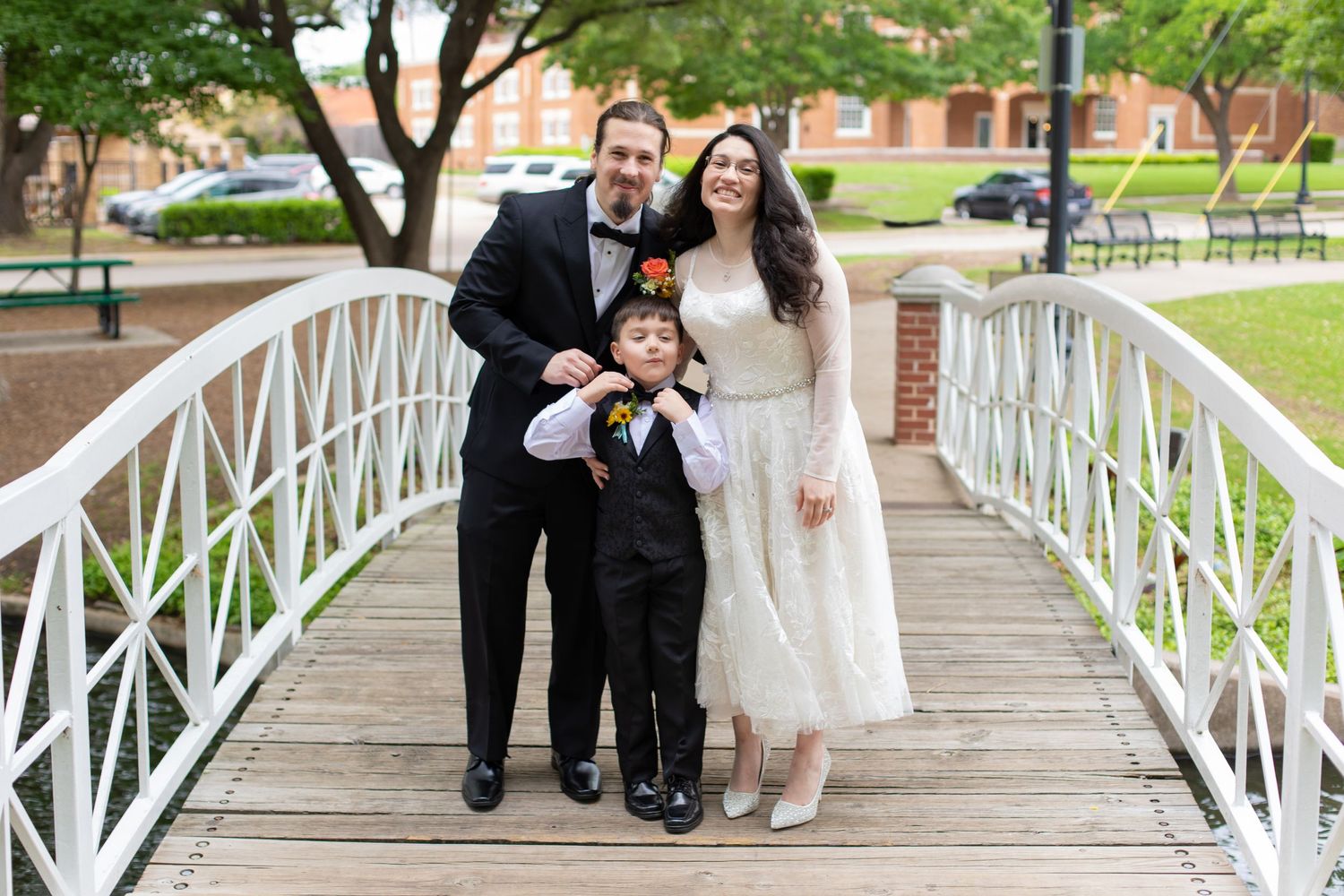 A wedding portrait of a family group standing together on an outdoor white bridge.