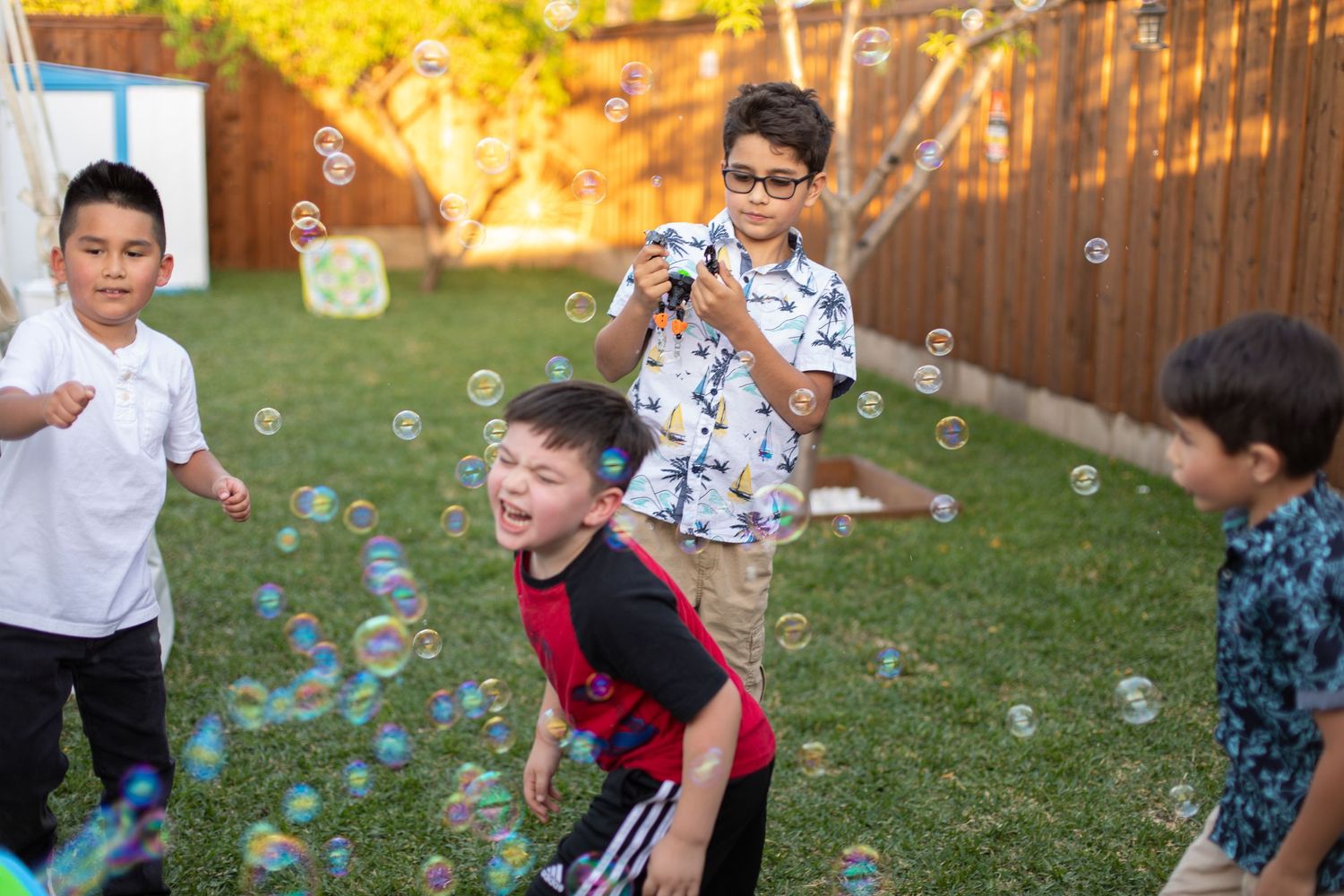 Kids playing and laughing with bubbles in a sunny backyard.